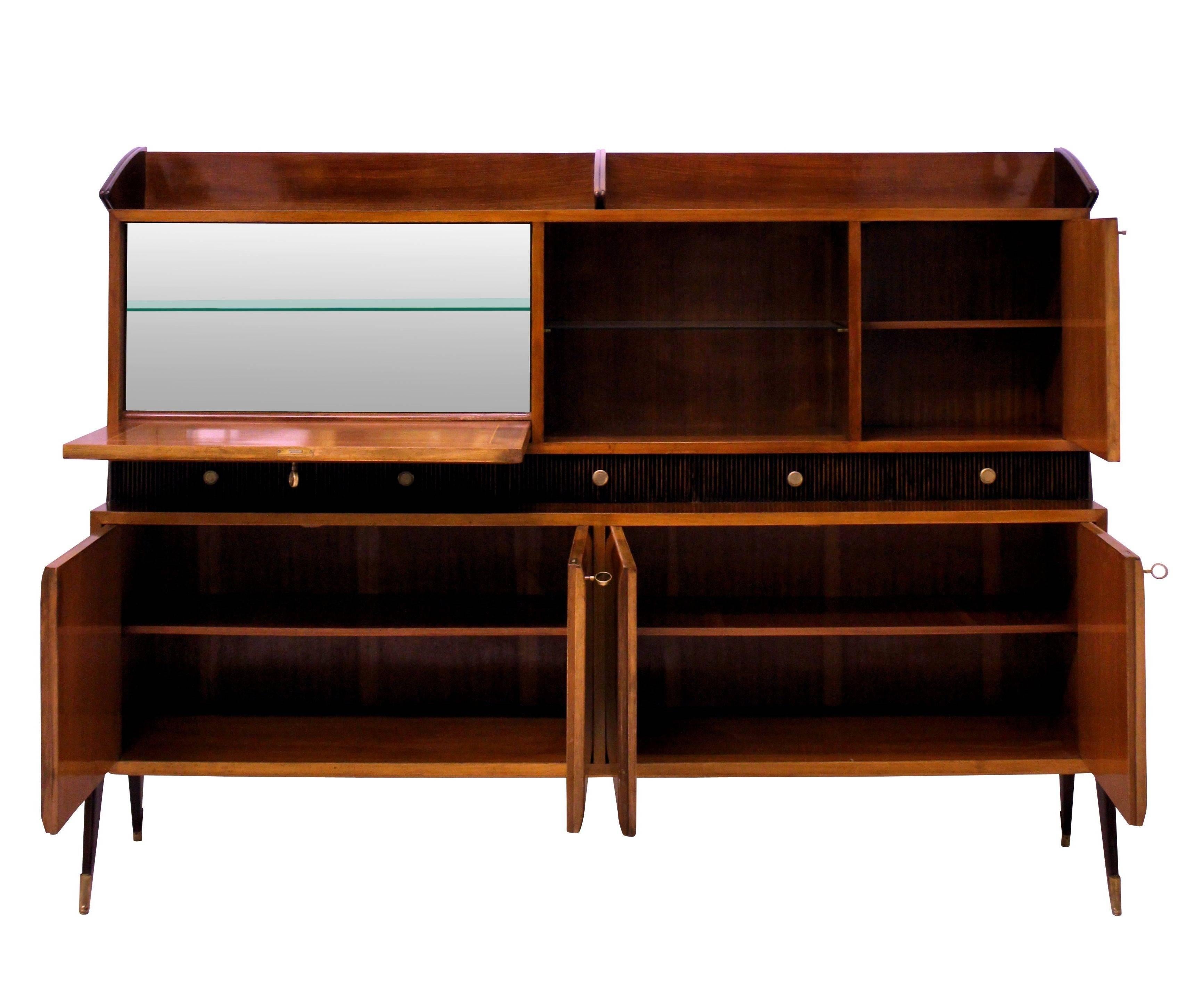 An Italian cabinet of very large proportions and of good quality. In rosewood and walnut comprising many lockable compartments, glass shelf, tambour fronted drawers and a mirror lined bar cabinet. Of architectural design with beautiful detailing in
