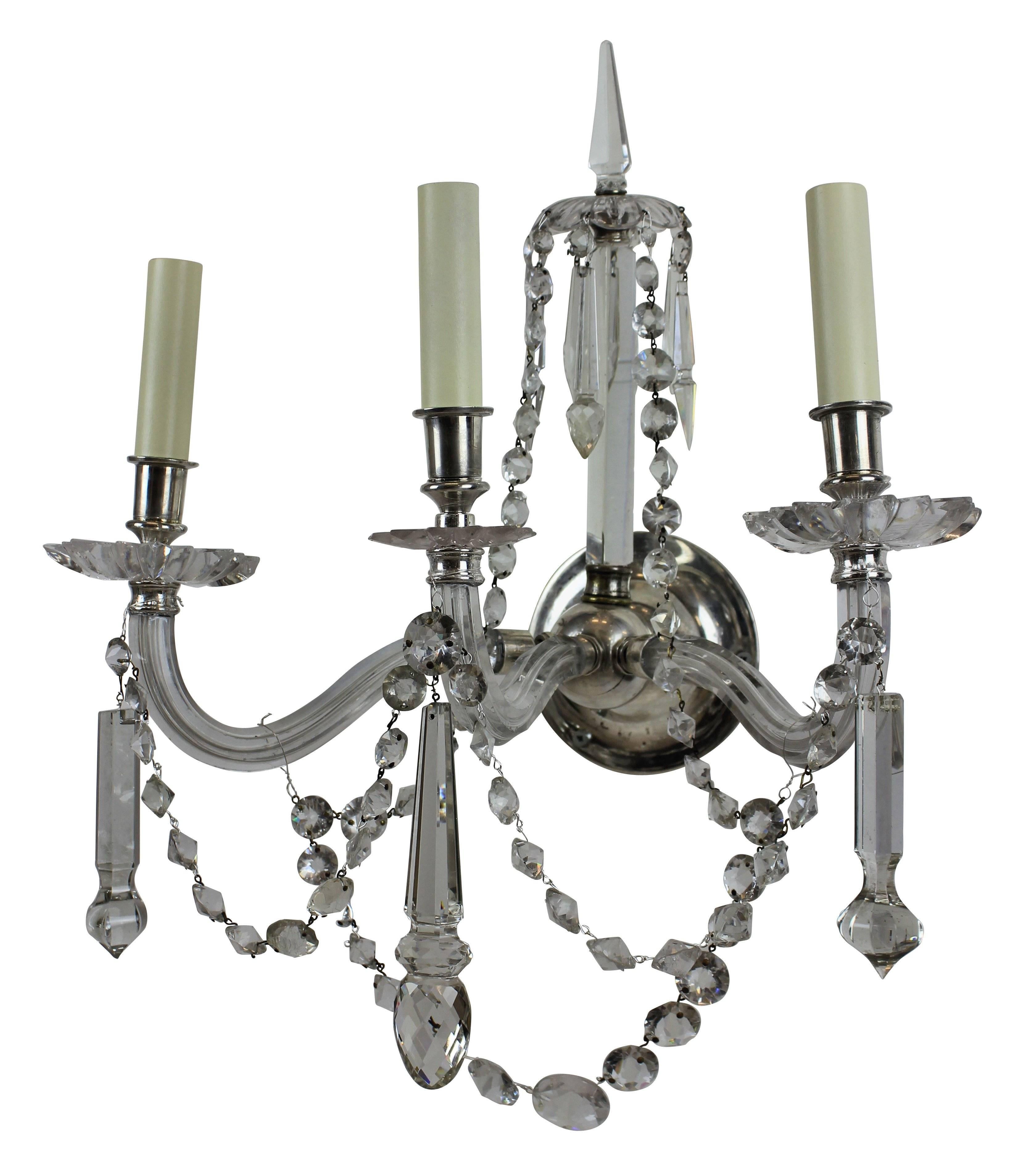 A set of four large English cut-glass wall lights, each with three braches, central spires and swags.
 