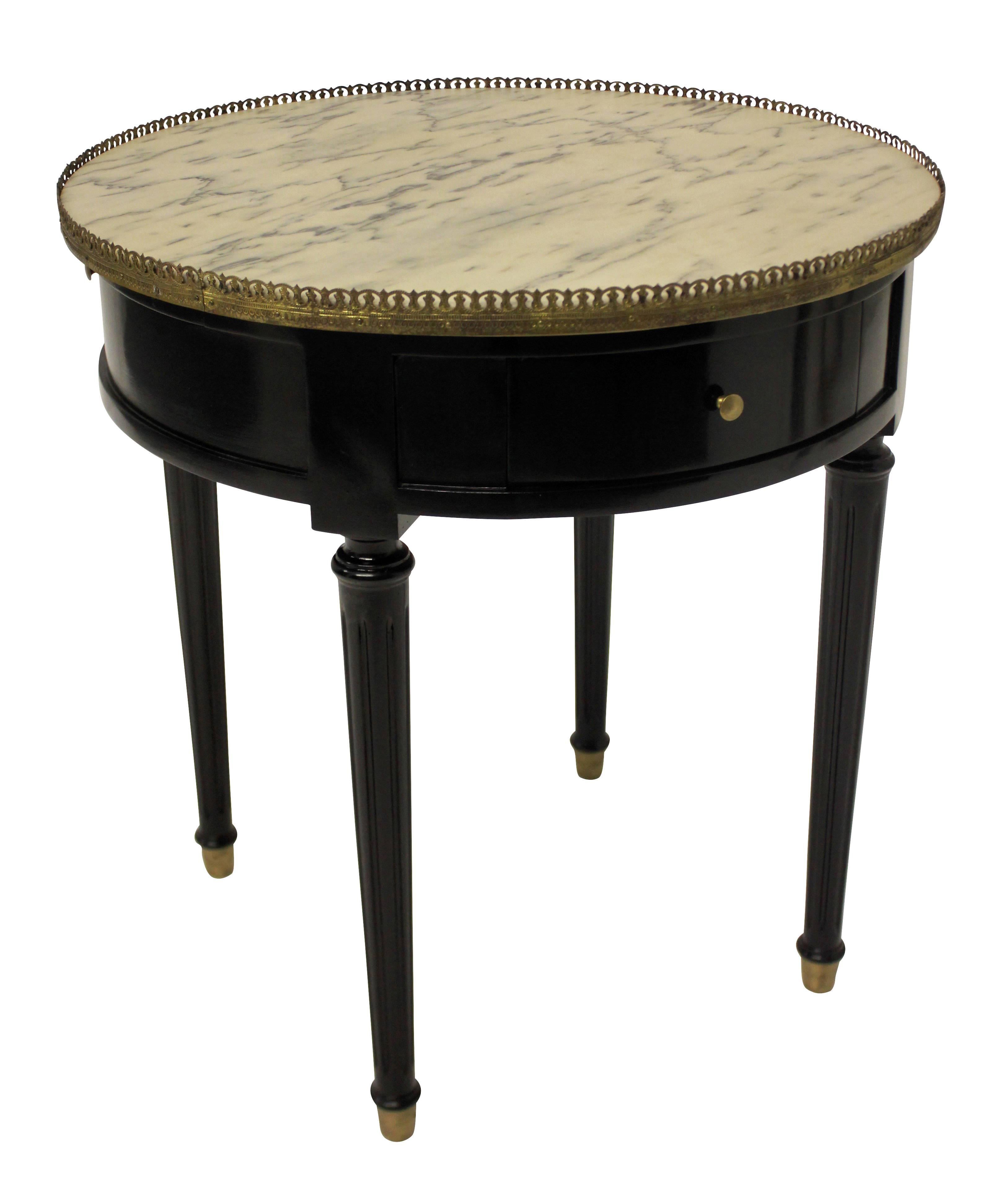 A French ebonized mahogany bouillotte table, with brass pierced gallery, marble top and brass sabot. Containing a single drawer and a blue leather covered slide.
