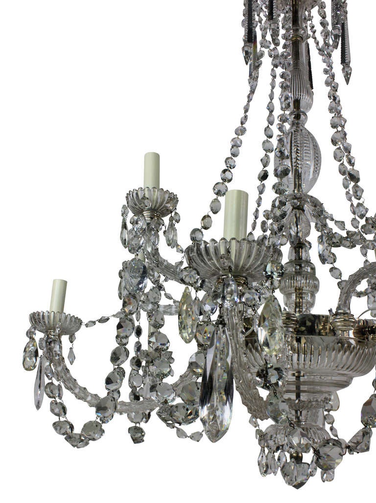 A fine English cut-glass chandelier of very fine quality by Perry & Co of New Bond Street. Tiered with twelve faceted scrolled branches issuing stellar cut pans and nozzles from lobed wells and baluster vase shaped column, hung with faceted pendants