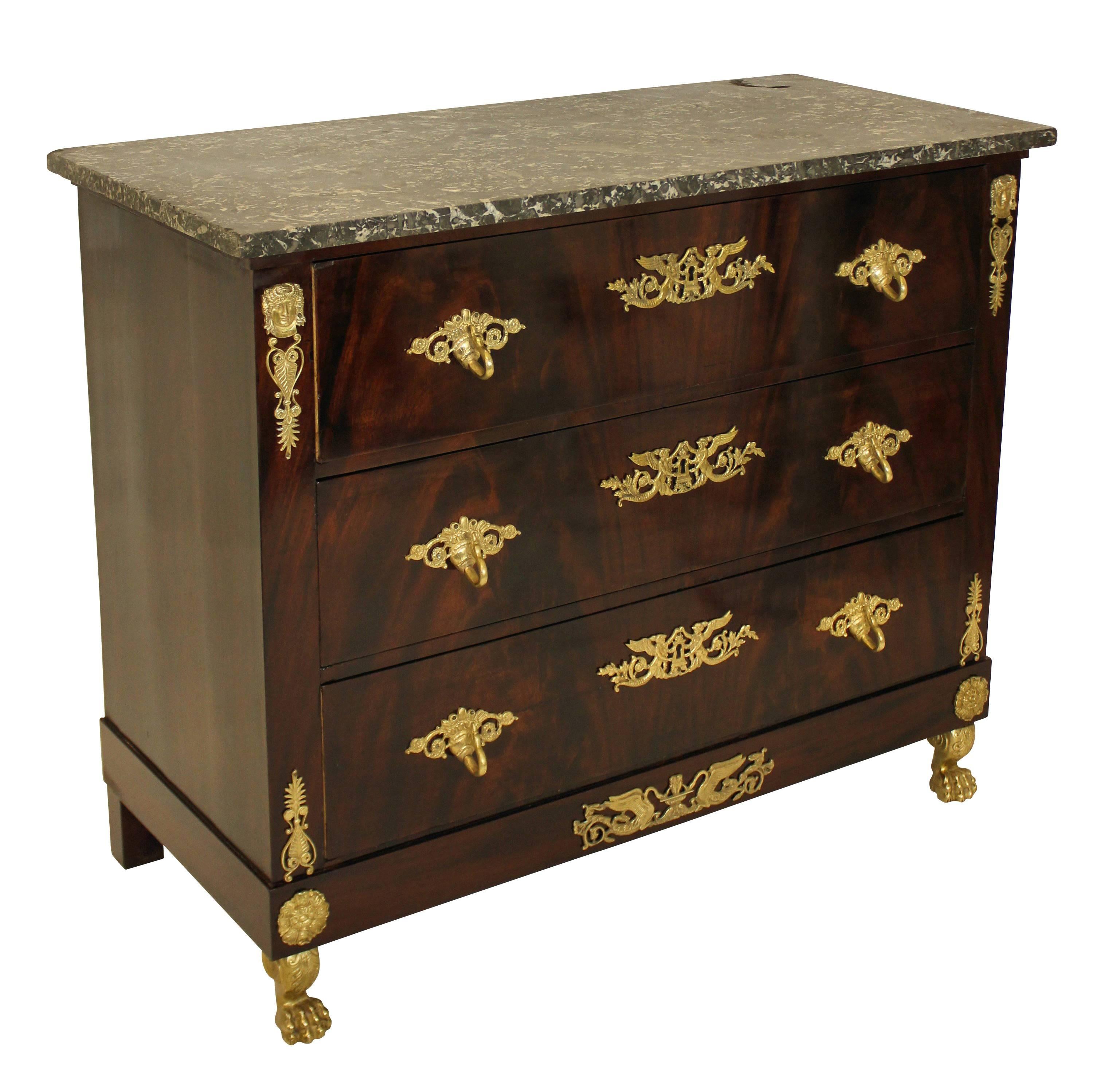 A French, First Empire commode of good quality. In flame mahogany, comprising four drawers, profusely decorated with gilt bronze mounts with detailed gilt bronze lion paw feet and a Belgian fossil marble-top.