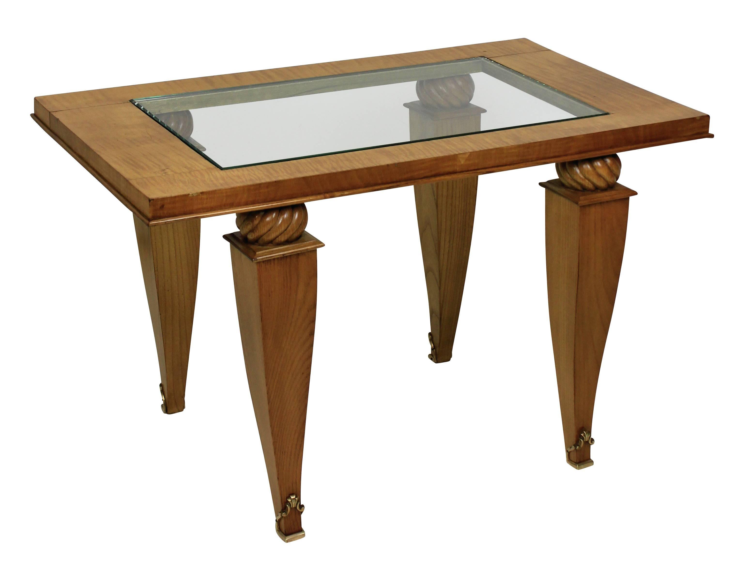 A French occasional table in fruit wood and maple in the style of Jules Leleu (1883-1961). With a glass inset top and gilt bronze sabot feet.