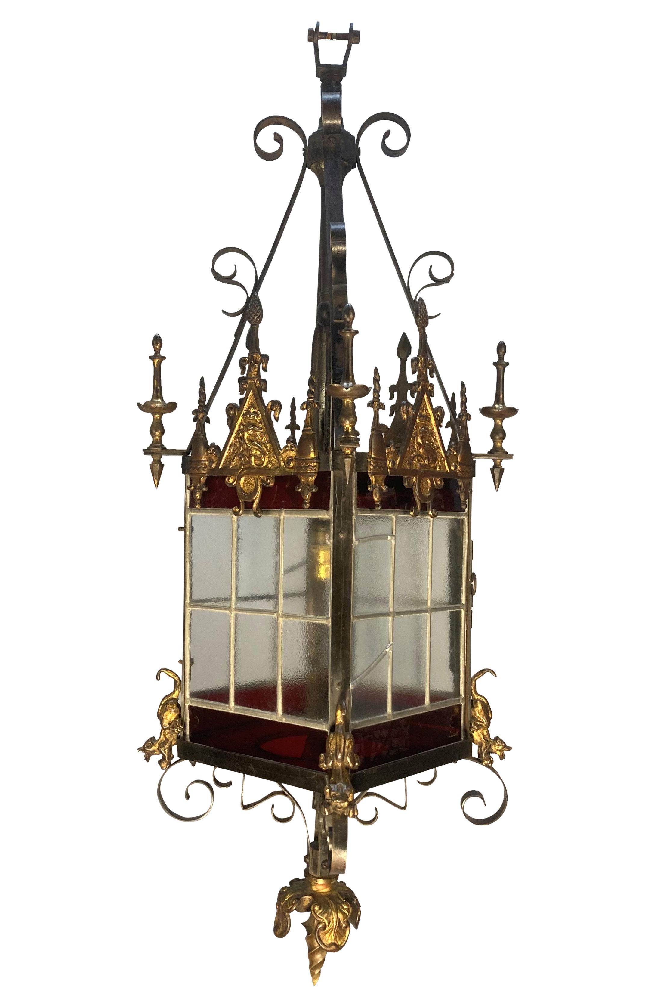 Lanterne gothique anglaise du XIXe siècle à la manière de Pugin, en fer forgé et bronze doré, avec quatre panneaux plombés comprenant des sections en rubis. Les éléments en bronze doré comprennent quatre tympans contenant un dragon et une couronne,