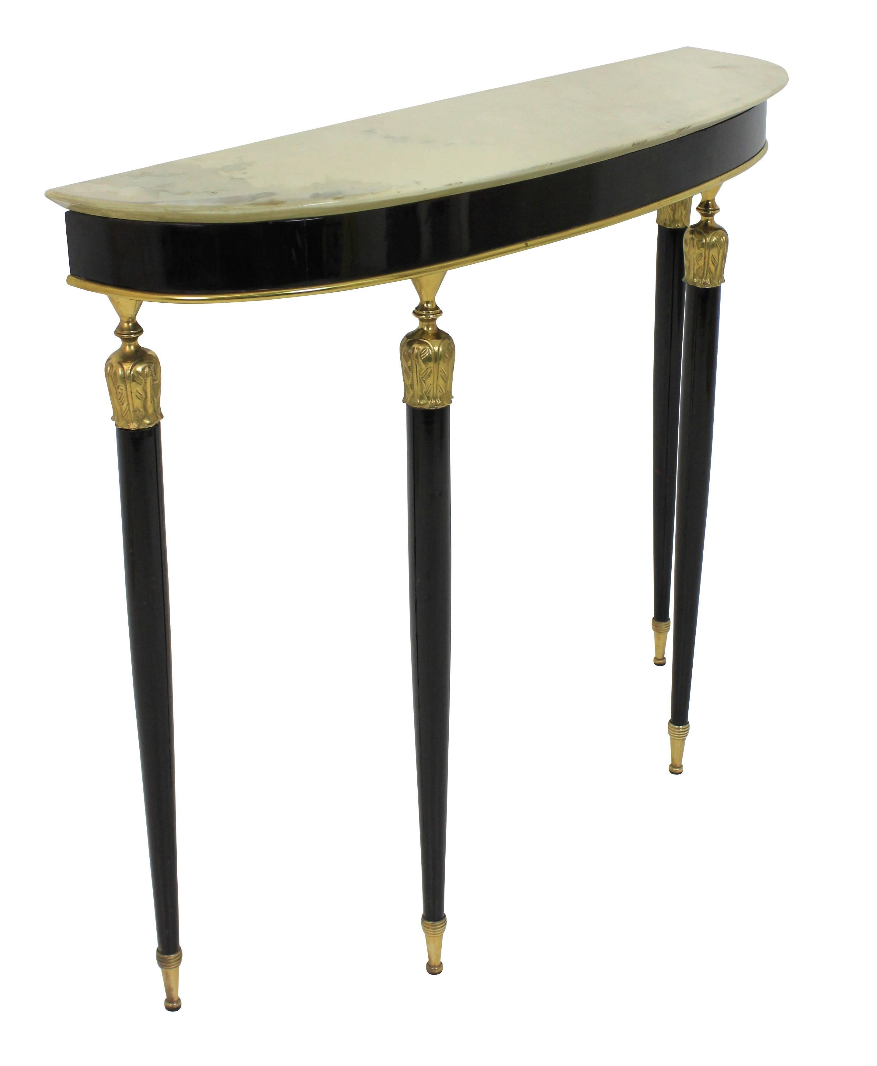 A stylish Italian demilune console table in black lacquer with brass mounts and sabot feet with a cream marble top.