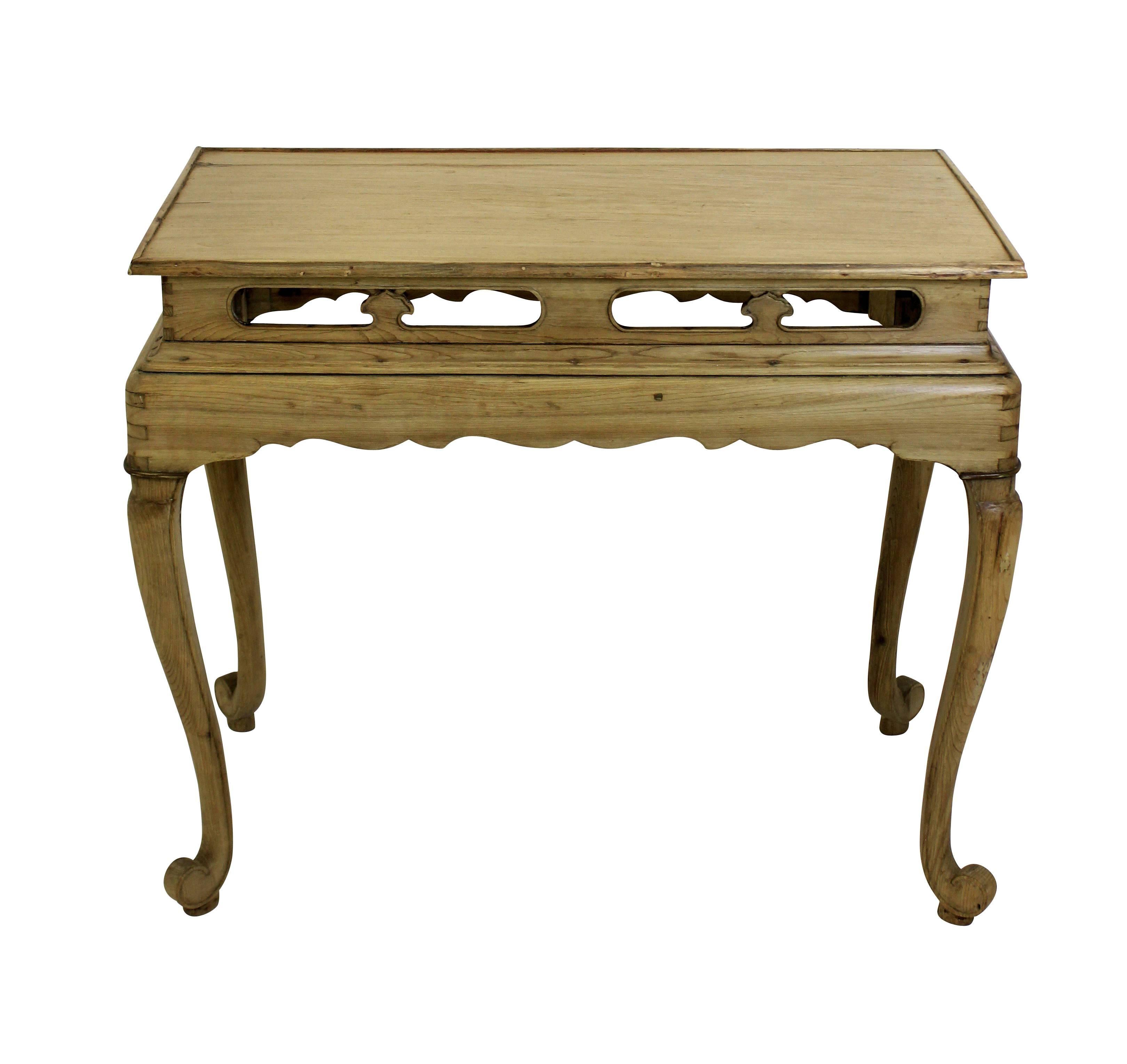 A Chinese stripped pine table of interesting design, with fretted panel frieze and cabriole legs.