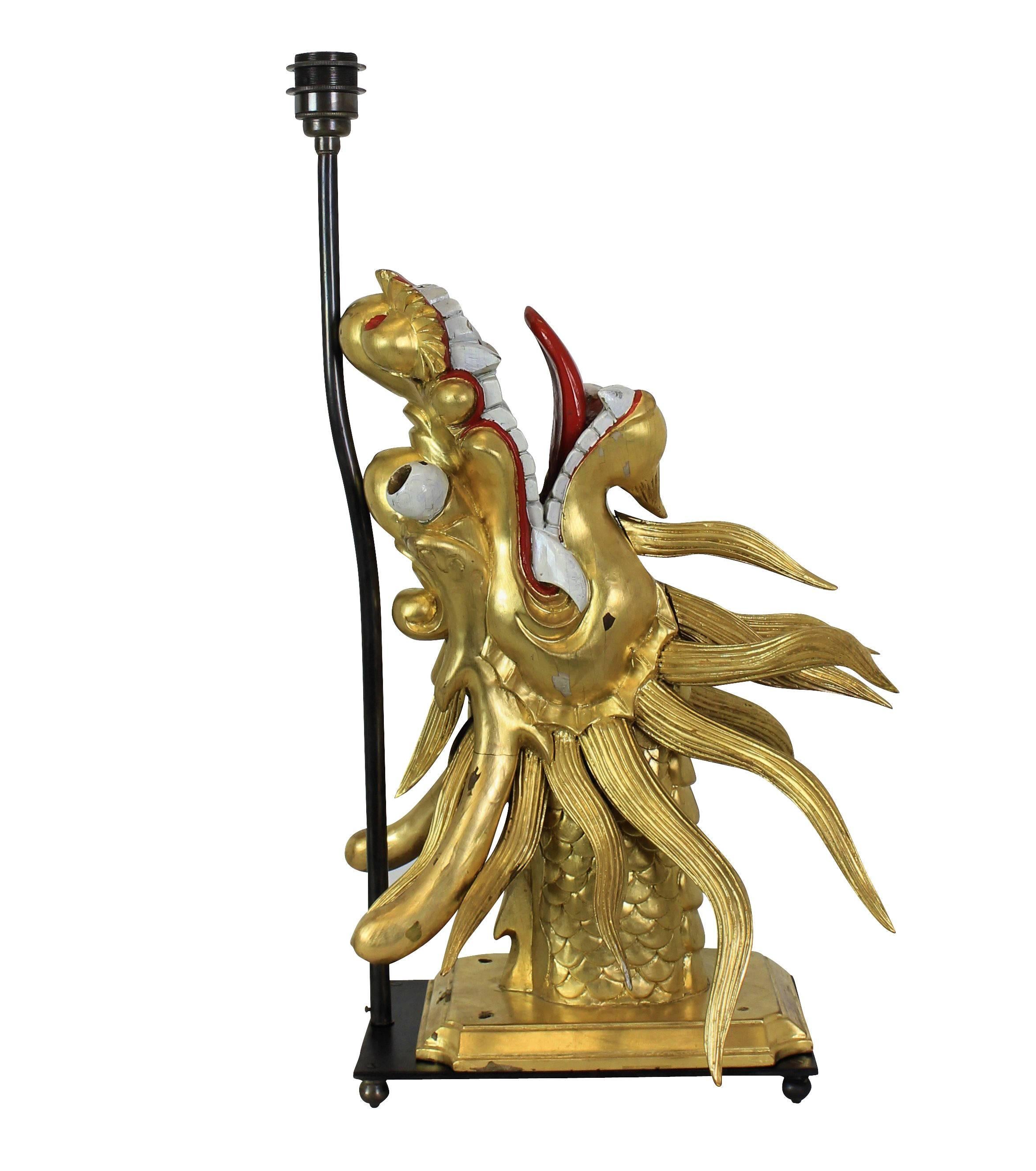 A pair of Chinese, carved, water gilded and painted dragon heads turned into table lamps on bronze bases.
  