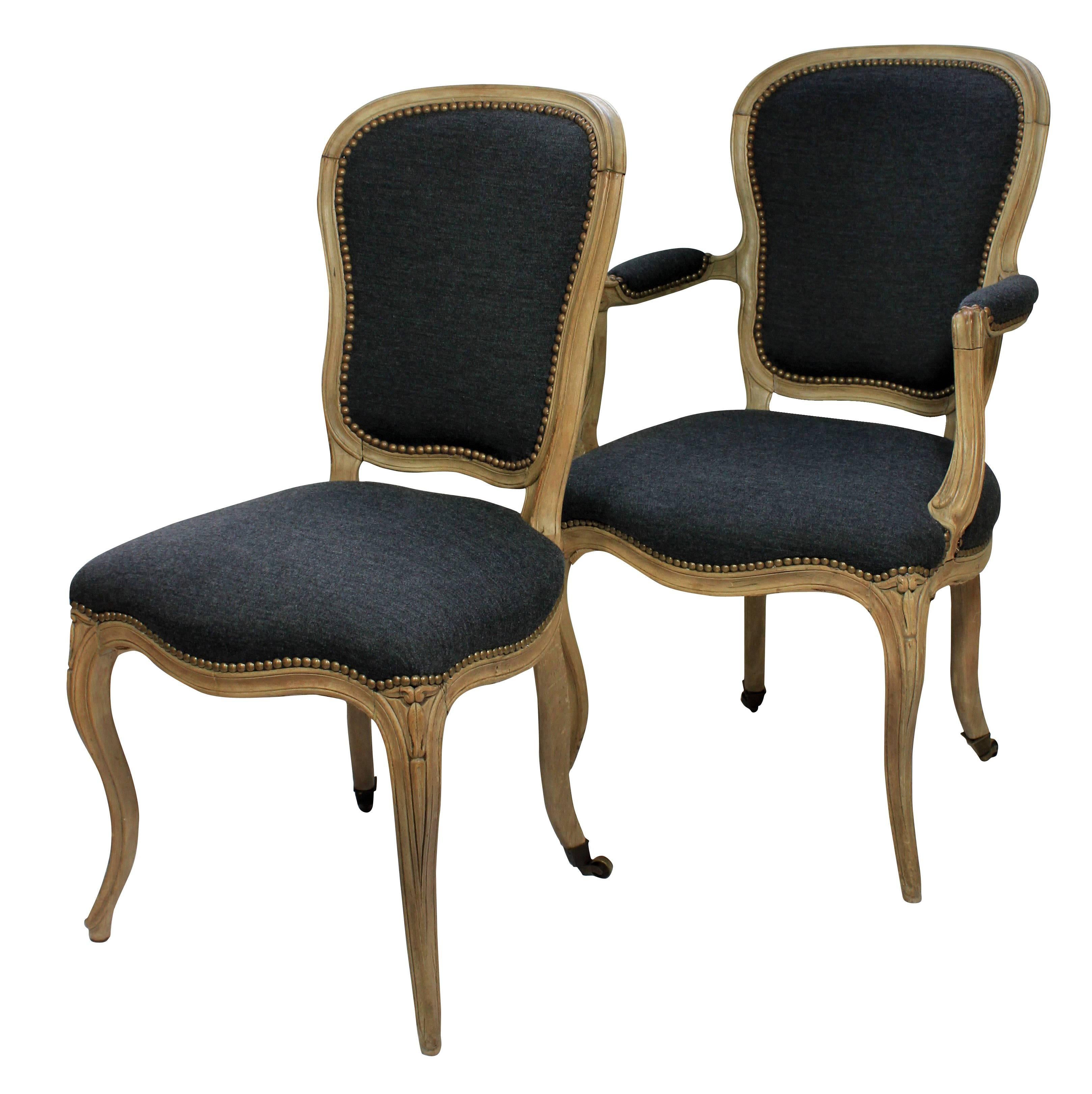 A set of four French dining chairs in bleached fruitwood, comprising two carvers and two side chairs. Newly upholstered in grey fabric.