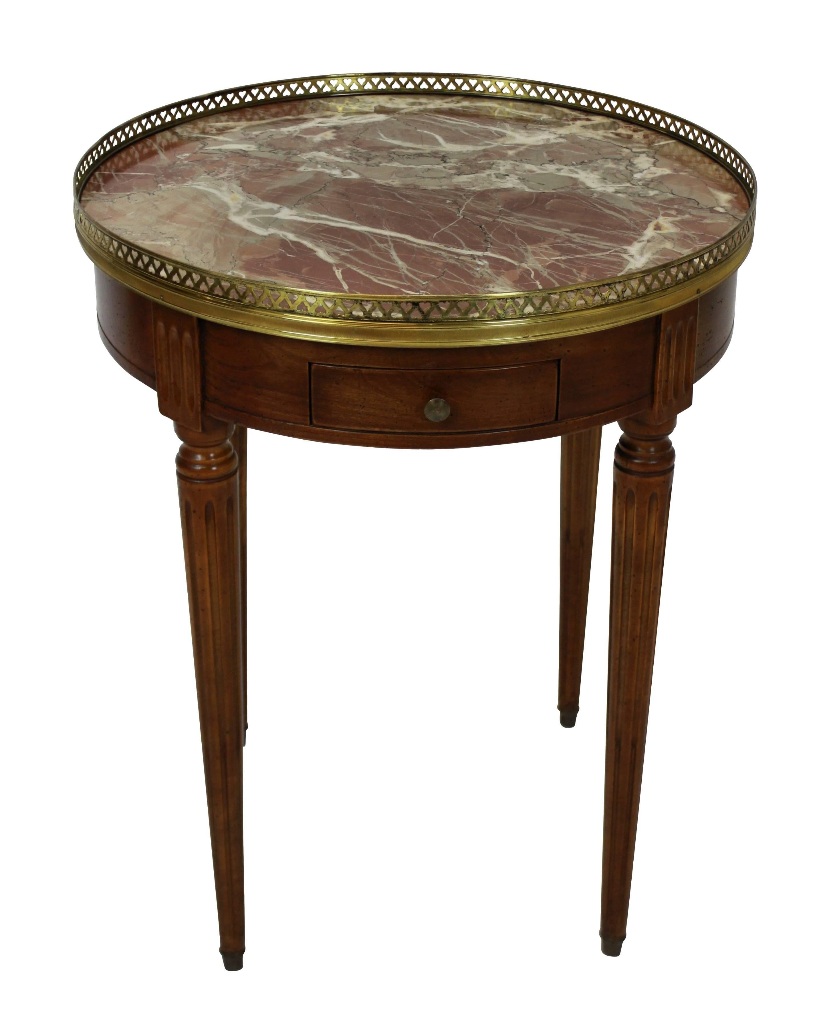 A French Bouillotte table in walnut, with a fine pierced brass gallery and sabot feet, fluted tapering legs, drawers and slides. The top of antico rouge marble.
 