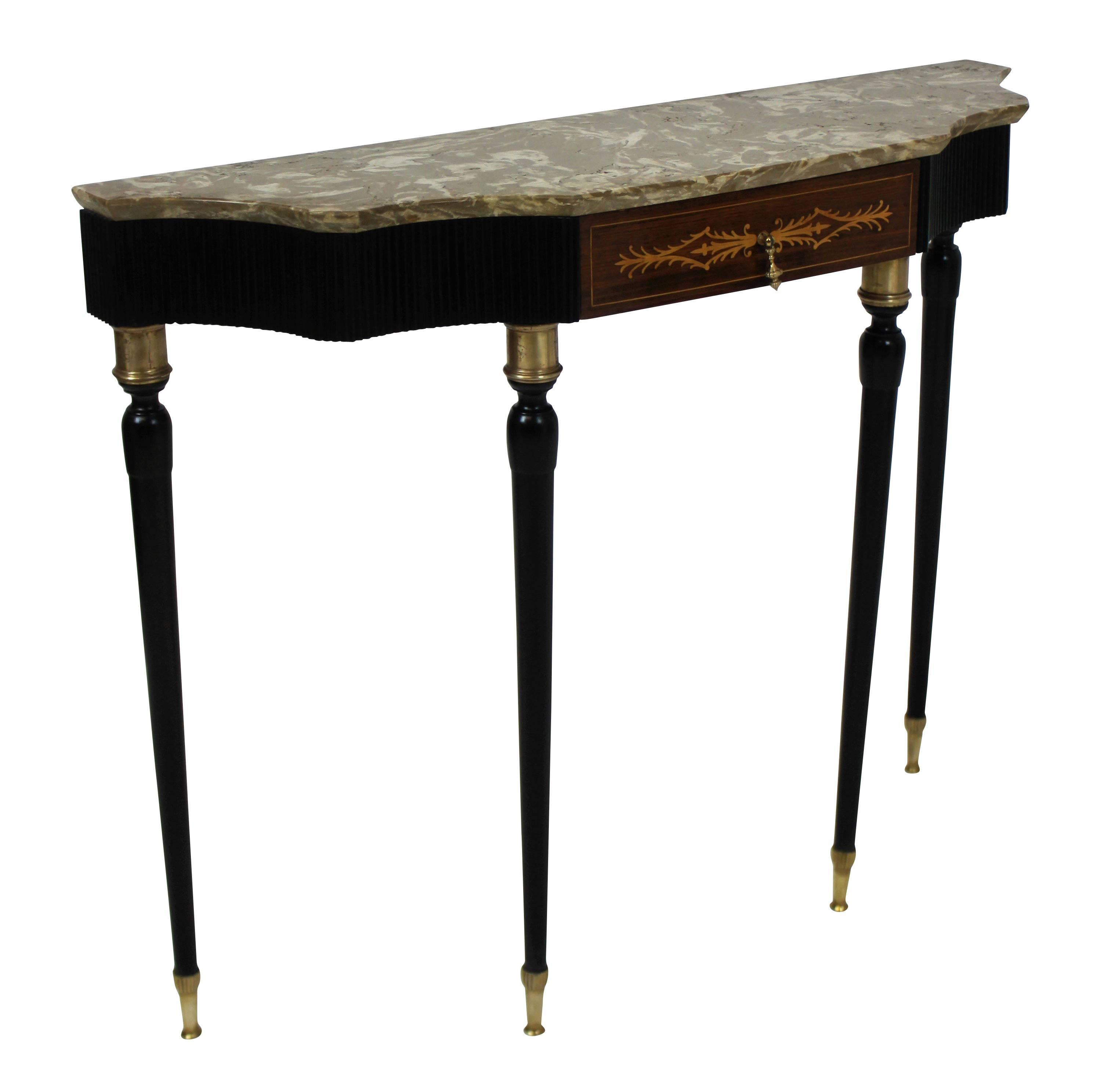 An elegant console table by Paolo Buffa, with ebonised tapering legs and tambour frieze. The central drawer with marquetry decoration. Brass fittings throughout and a beautiful fossil marble-top in a putty colour.
 