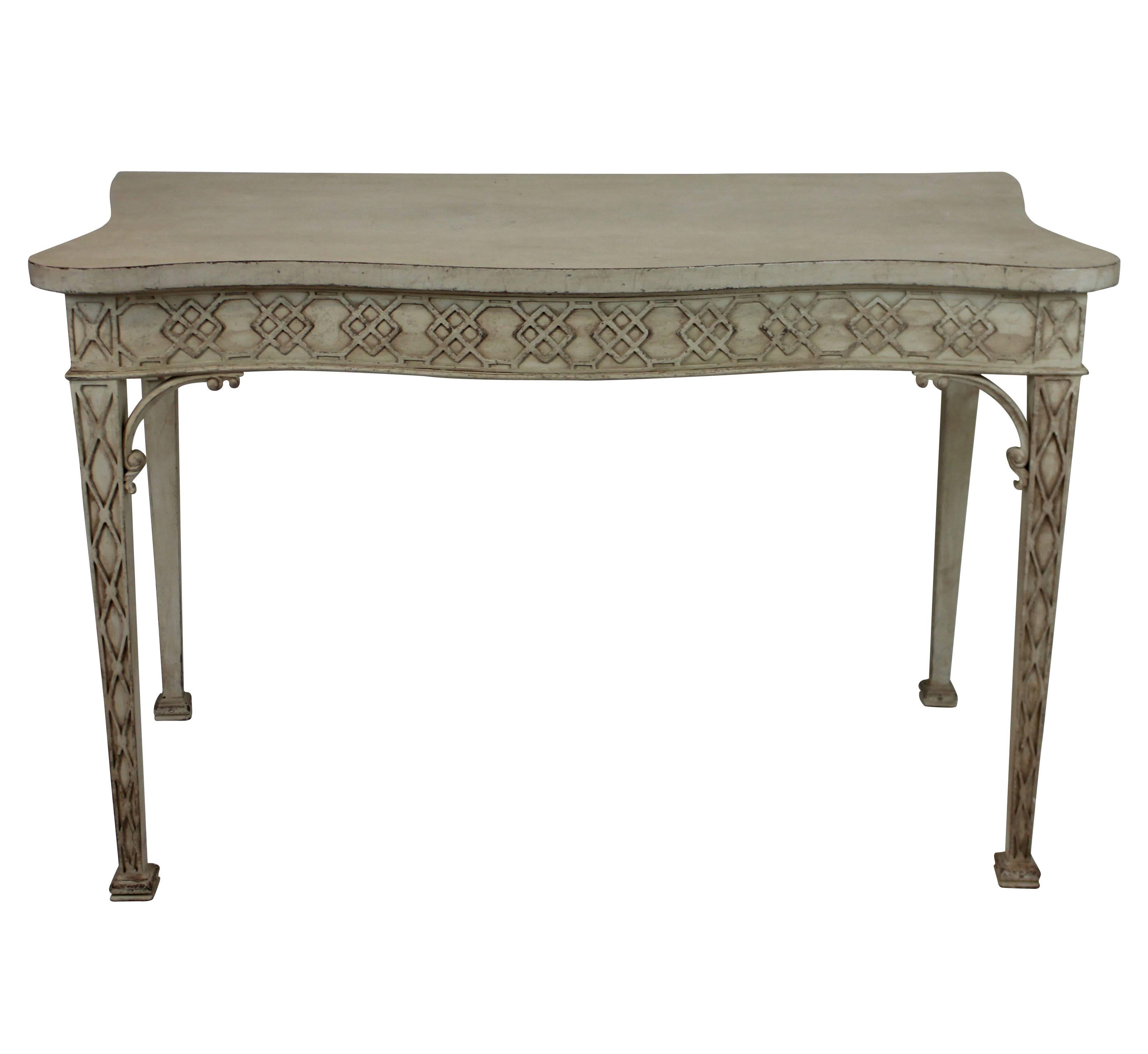 A large English painted console table in the manner of Chippendale. With a serpentine front and lattice work frieze and tapering legs.
    