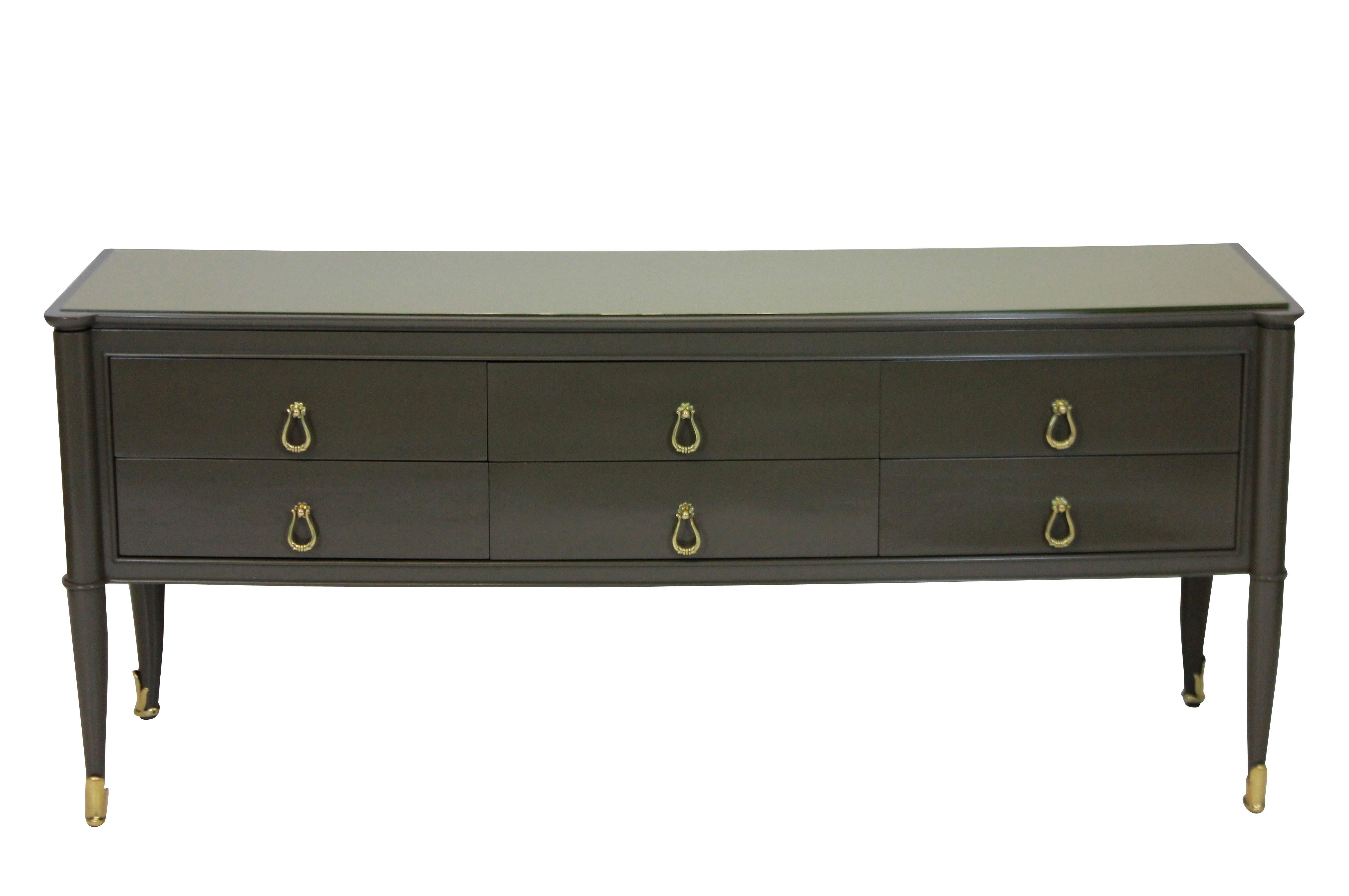 A stylish Italian six-drawer credenza in an Armani grey lacquer, with a golden colored glass top and brass fittings and sabot.
  