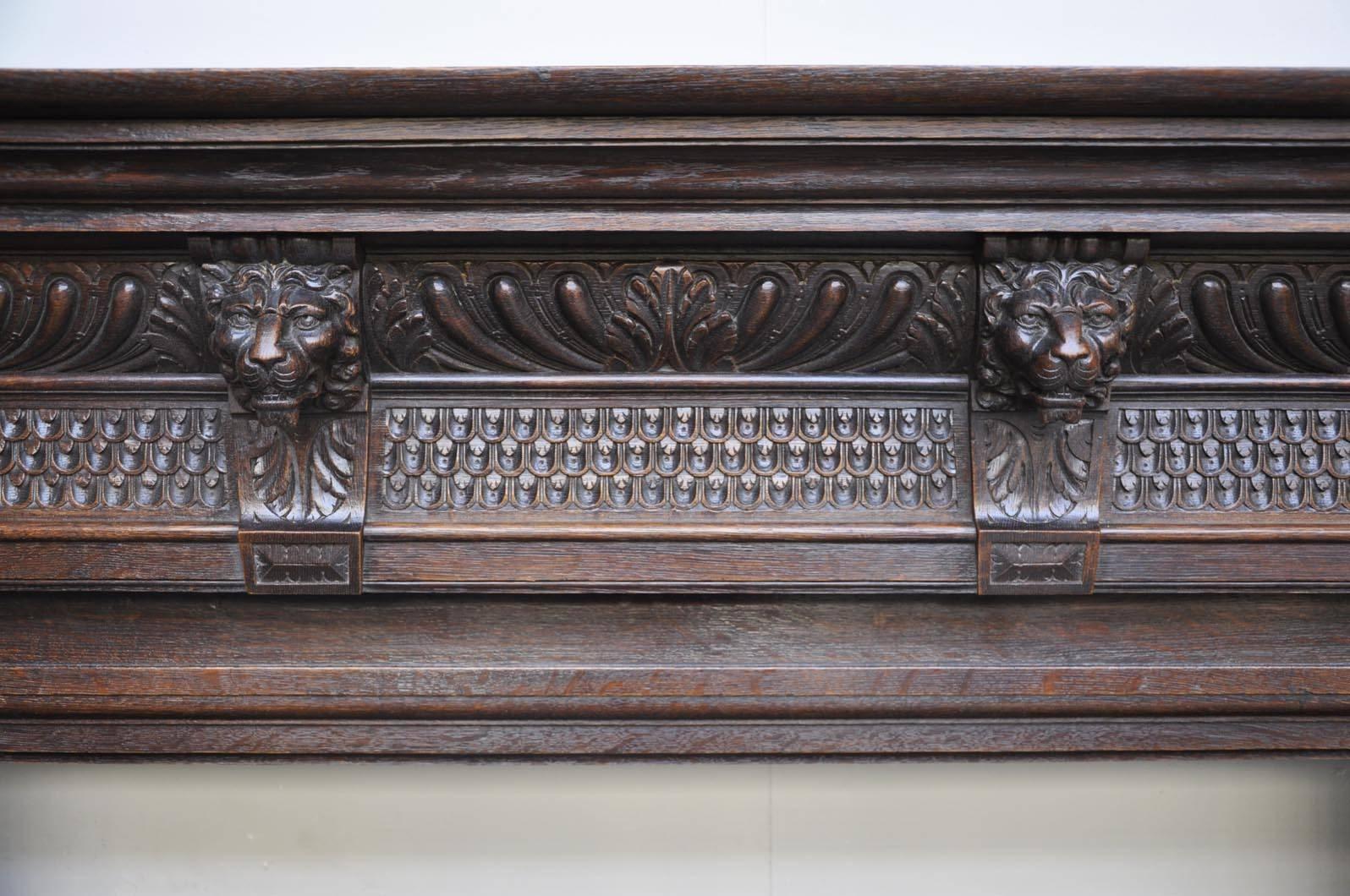 This fireplace is made out of oak, finely carved with a frieze of four lion's heads, godroons and acanthus leaves. We can see two fluted columns with a Corintian capital.