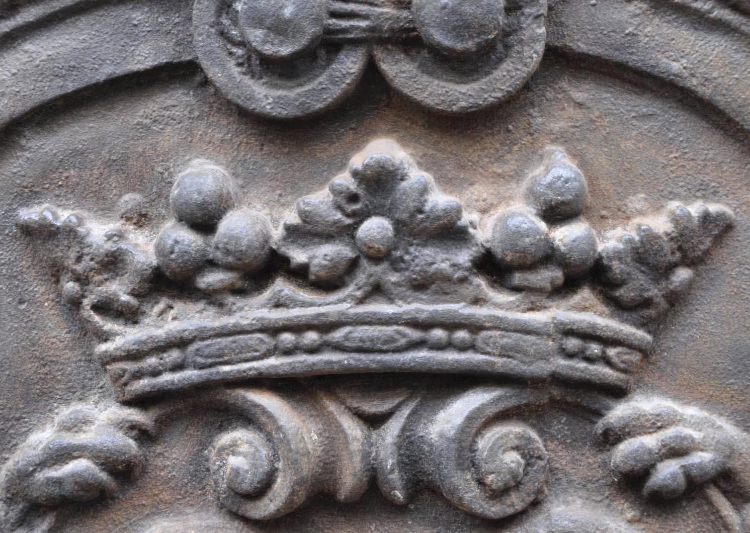 This big fireback in cast iron have an heraldic decor with lions framing a crown and a coat of arms. A burnished toch, symbol of the fire in the mantel, is on the Summit of the fireback. Made during the 20th century, this beautifull fireback is in