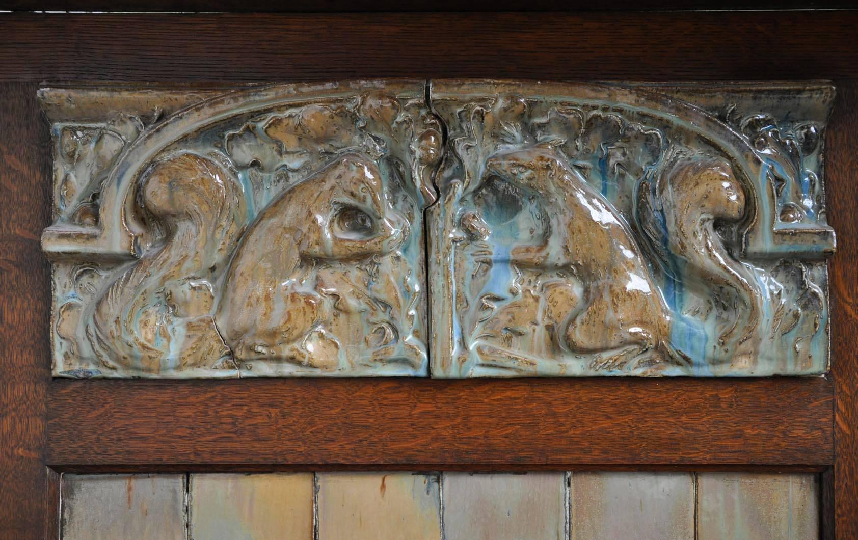 This rare Art Nouveau fireplace was made out of oak wood and ceramic and is attributed to Charles Gréber from the Gréber Manufacture. The upper part is ornated with a frieze with two squirrels and Art Nouveau columns with foliages. 
Legs are