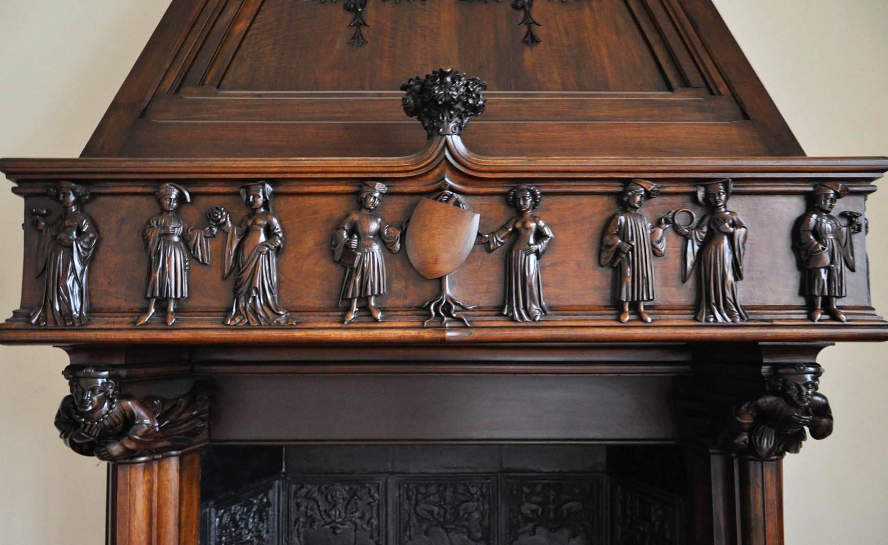 This monumental antique Neo-Gothic style fireplace was carved in walnut during the 19th century. 
The frieze is decorated with medieval courtly scenes. The fireplace is crowned by a trapezoidal hood with  manticores figures.
The fireplace is sold