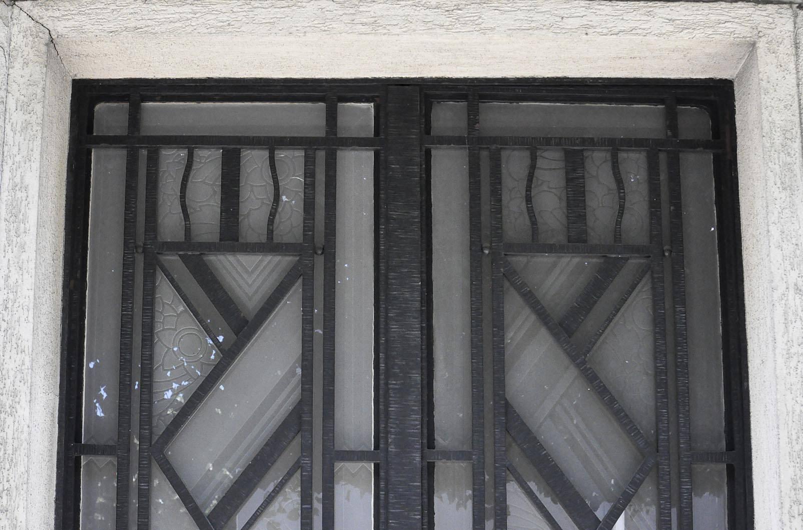 This beautiful double door in Art Deco style was made circa 1930. Its symmetrical ironwork frames engraved glass panels alternating straight lines and stylized flowers. It is a rare period work.