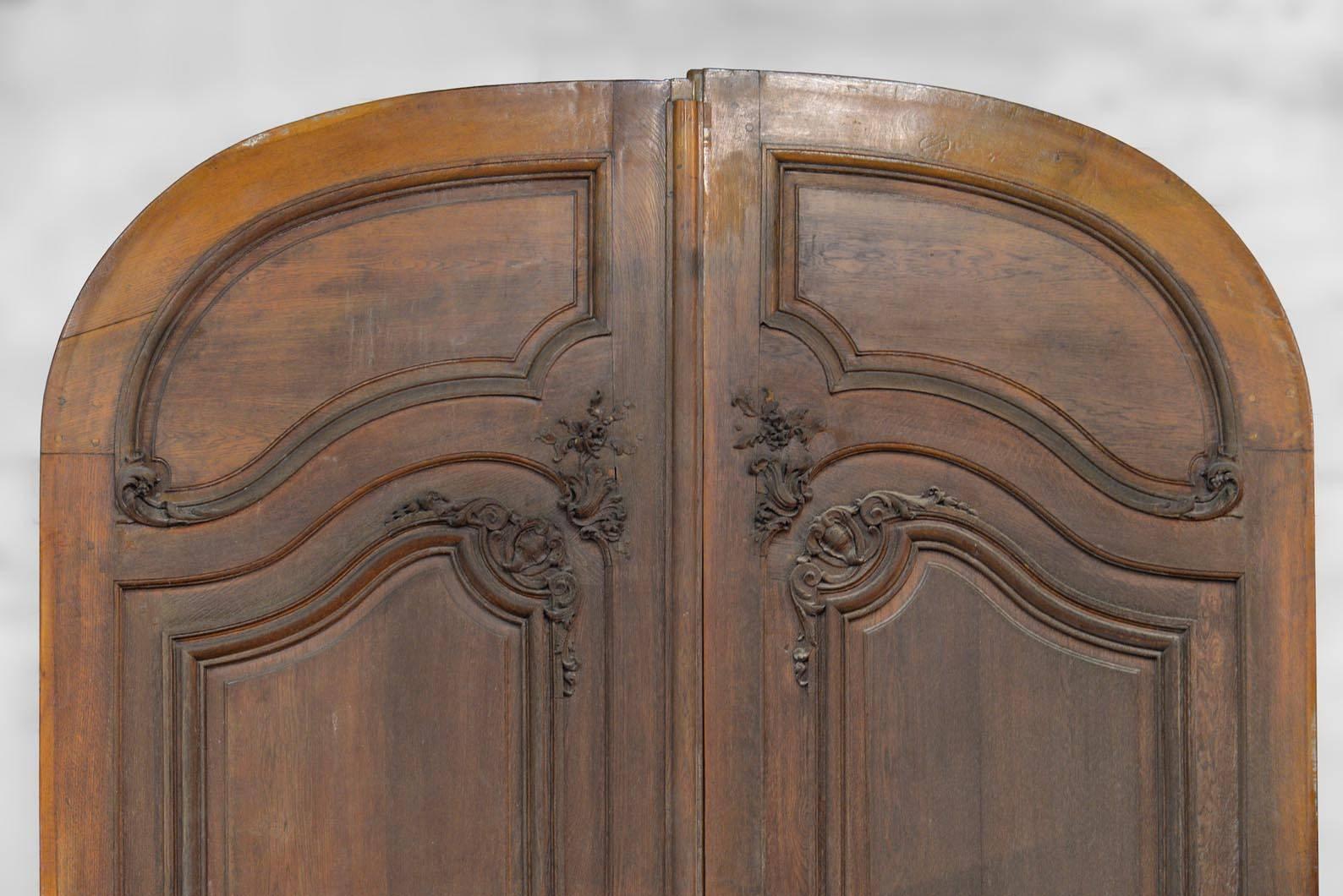 These high oak doors were built in the late 19th century. In very good condition, the details were carefully executed:Fine moldings discretely rhythm the structure, as well as the inlaid marquetry panels at the bottom of the doors. The sleek design