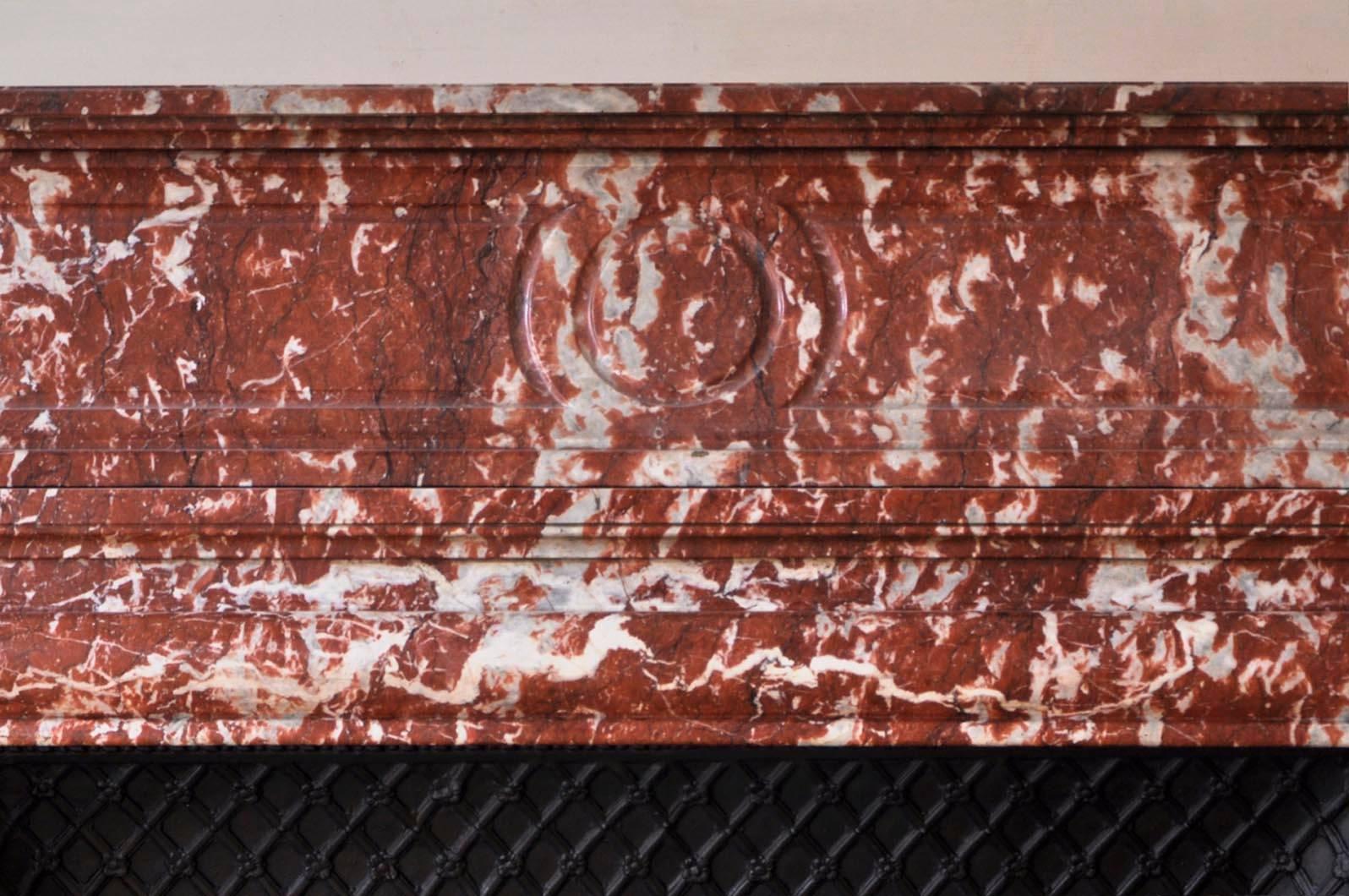 This Louis XIV style antique fireplace in red Languedoc marble was made in the 19th century. A wide moulding highlights the opening to the firebox. The fireplace is topped with an acroterion subtly decorated with moulded panels.

This fireplace is