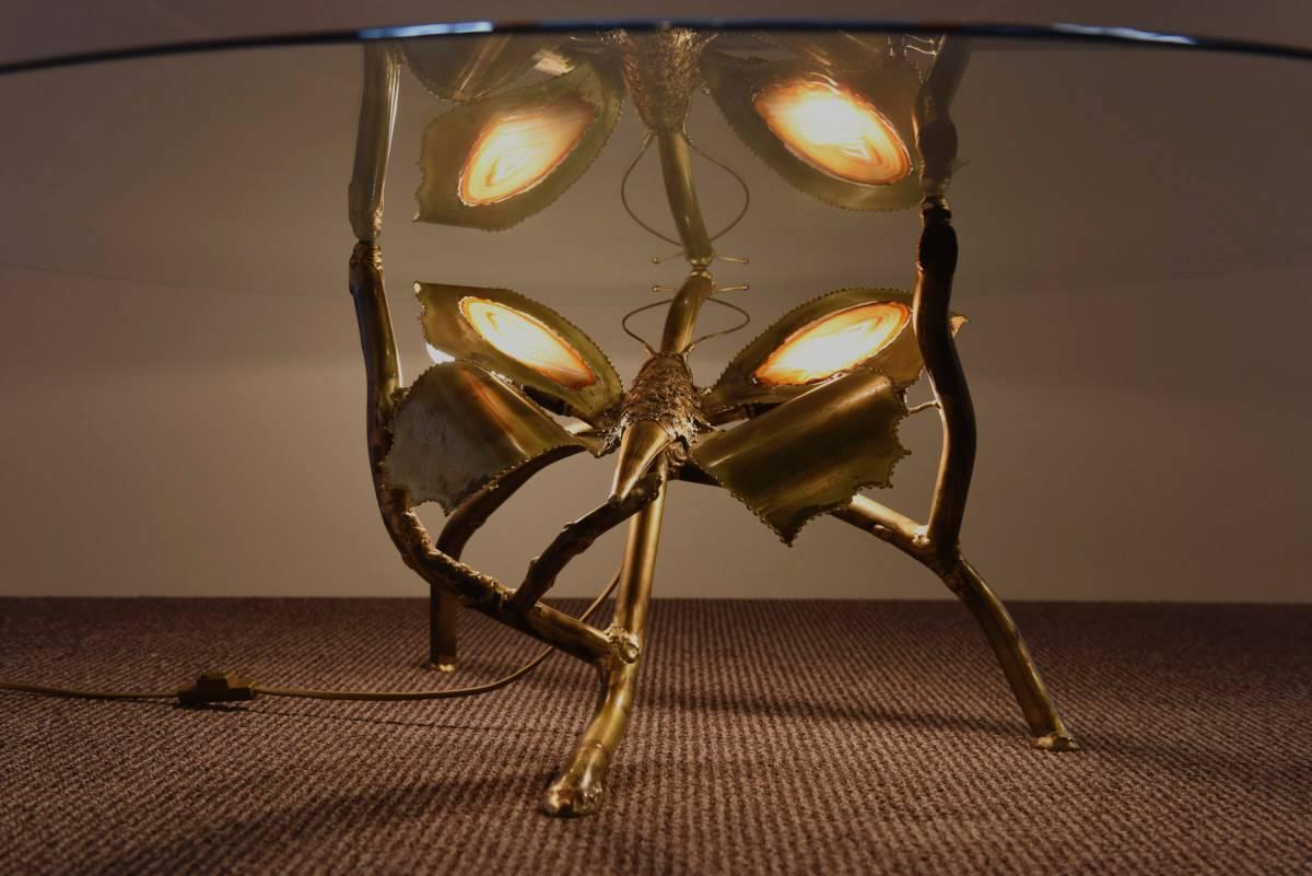 Butterfly inspired brass coffee table designed and edited by Jacques Duval Brasseur in the 1970s.
The illuminated wings containe an agate stone in which the light comes through. A round glass top is placed on it. A rare and spectacular piece.