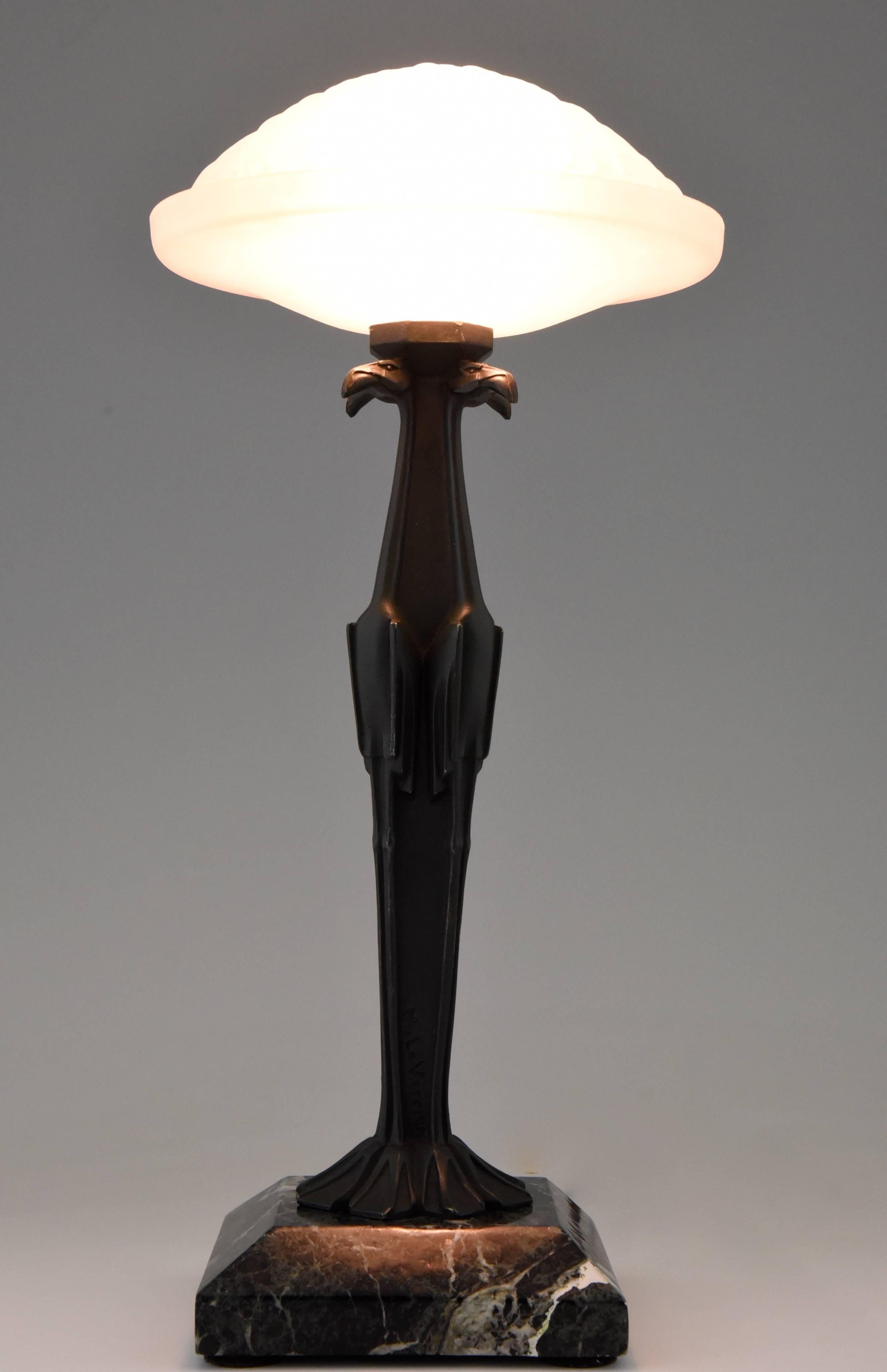 Art Deco flamingo table lamp with glass shade. 

Artist/Maker:
Max Le Verrier. 

Signature/Marks: 
M. Le Verrier. 

Style:
Art Deco.

Date:
1930.

Material: 
Dark green patinated metal.
Dark green marble base.

Origin: