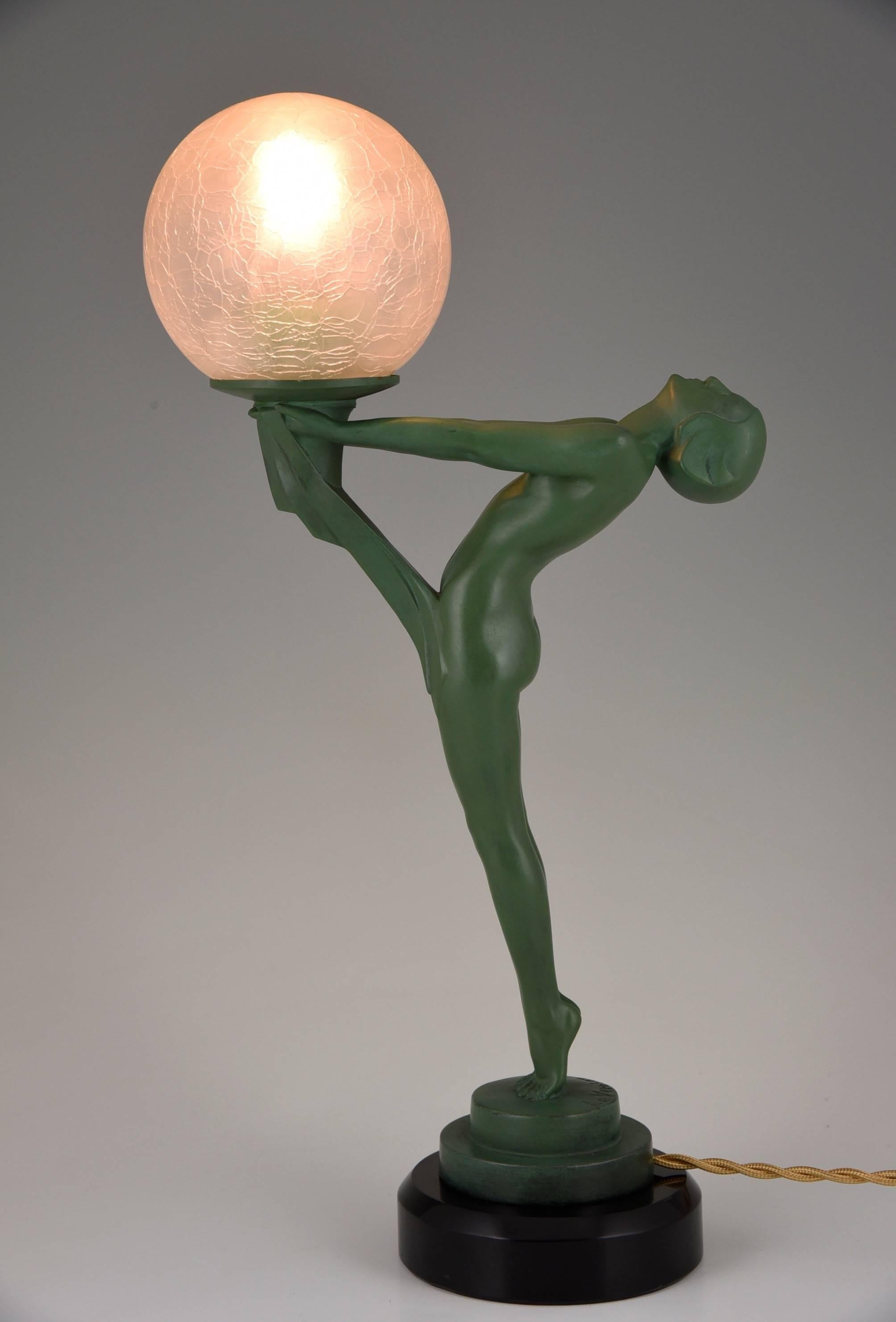 Art Deco figural table lamp of a standing nude holding a glass shade.

Artist / Maker:.
Max Le Verrier. 

Signature / Marks: 
Le Verrier. 

Style:
Art Deco.

Date:
1930.

Material: 
Green patinated metal.
Black marble base.
Crackled