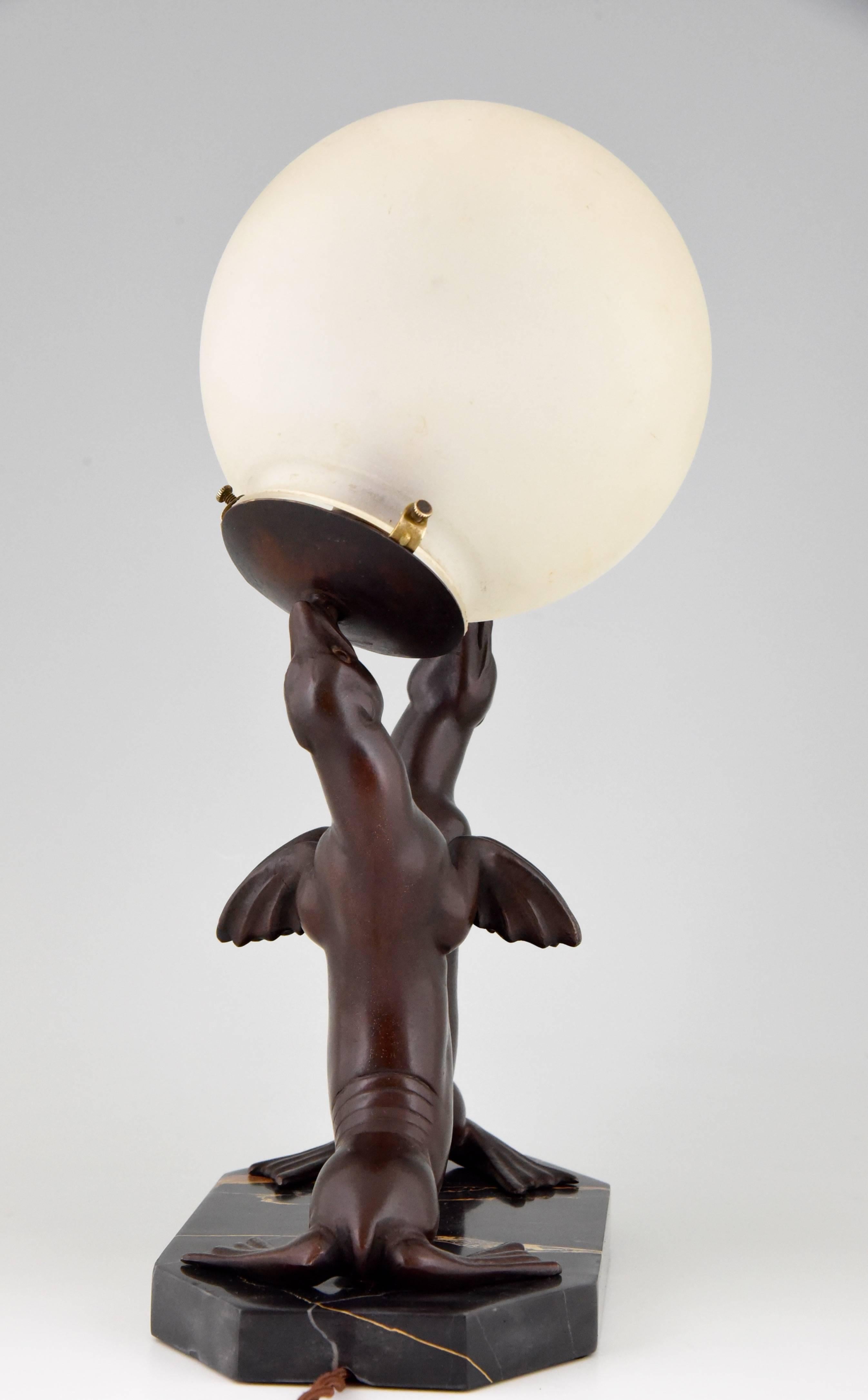 Description: 
Art Deco lamp of two seal playing with a ball. 

Artist Maker:
Louis Albert Carvin.

Signature / Marks: 
Carvin. 

Style:
Art Deco.

Date:
1930.

Material: 
Patinated metal on a portor marble base.

Origin: 
France.
