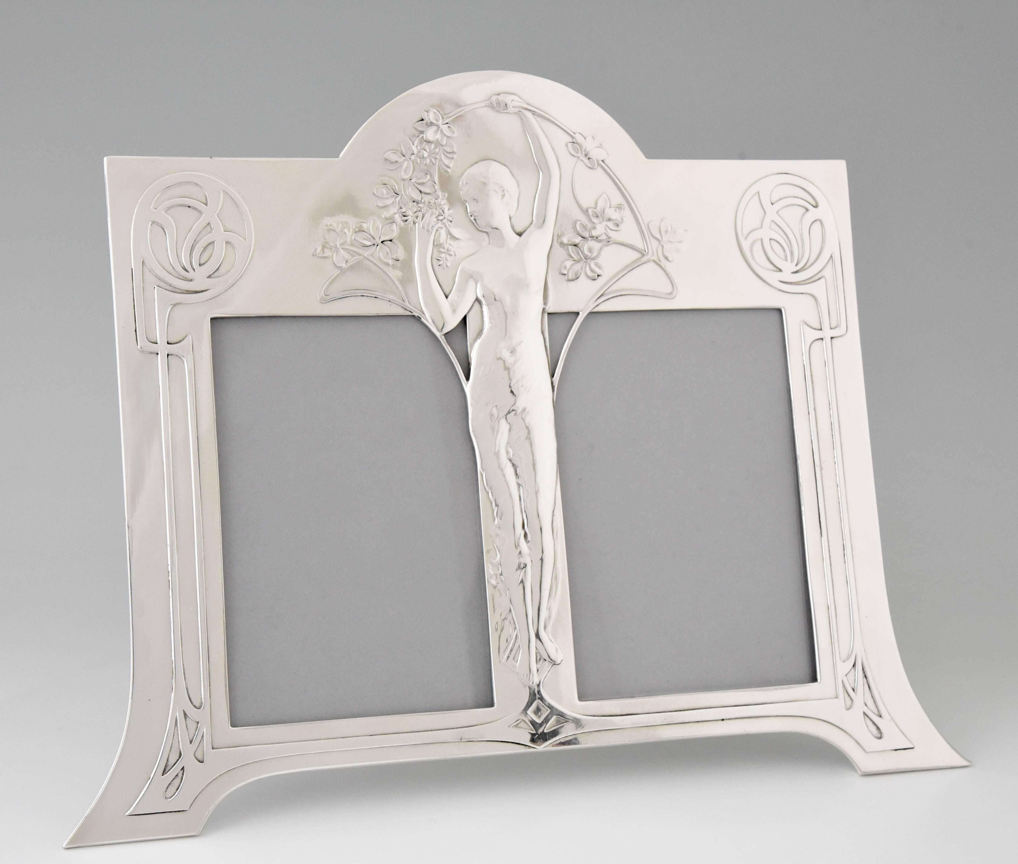 Description: 
Double photo frame with an Art Nouveau maiden holding a branch. 

Artist/ Maker:
WMF, Württembergische Metallwaren Fabrik. 

Signature/ Marks: 
WMF mark, B, ox.

Style:
Art Nouveau. 

Date:
1906. 

Material:
Britannia