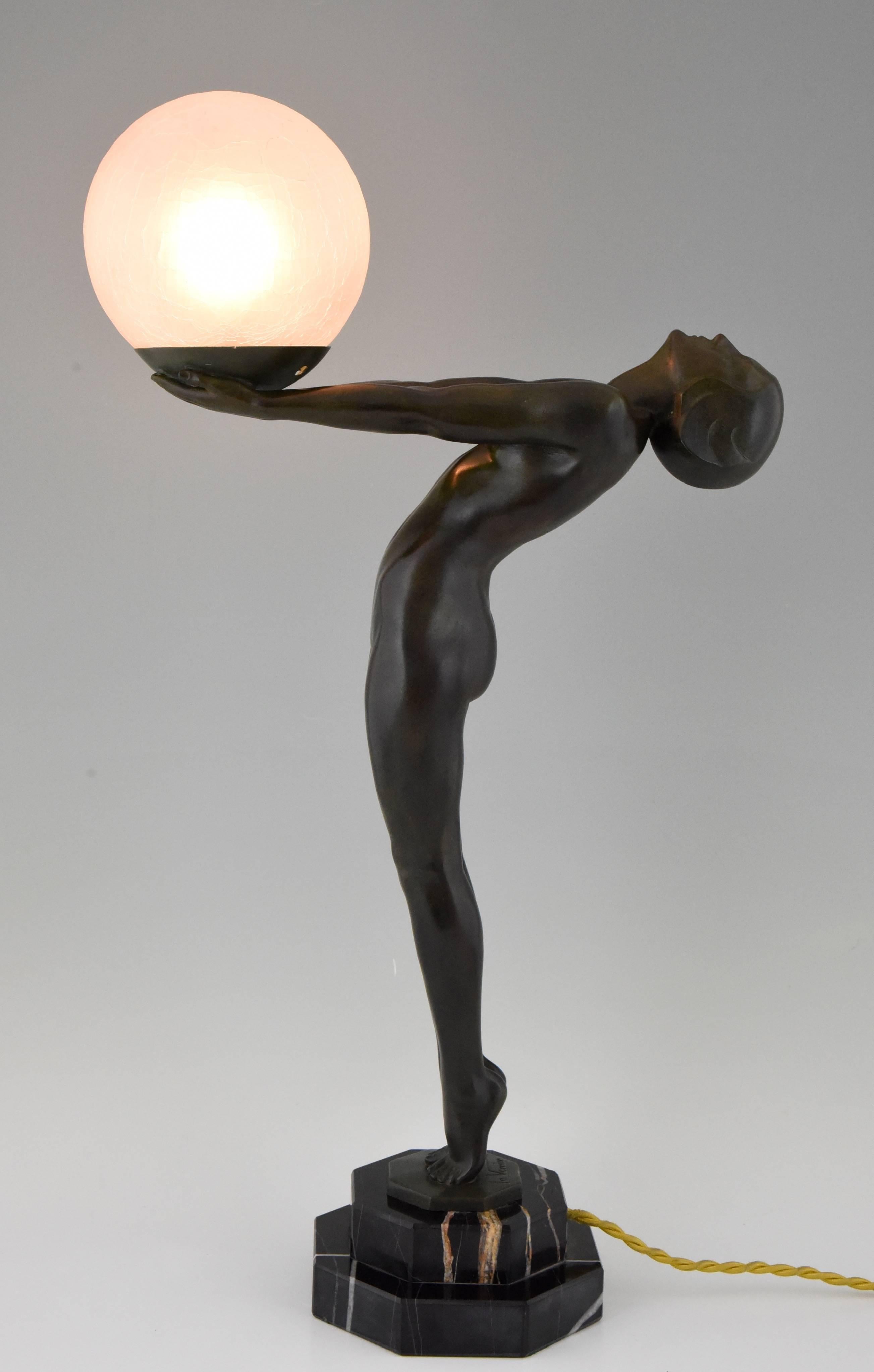 Stylish Art Deco lamp in the shape of a nude standing on her toes holding a ball. 
Artist/ Maker: Max Le Verrier.
Signature/ Marks: Le Verrier.
Style: Art Deco.
Date: 1930.
Material: Green patinated metal, marble base, crackle glass.
Origin:
