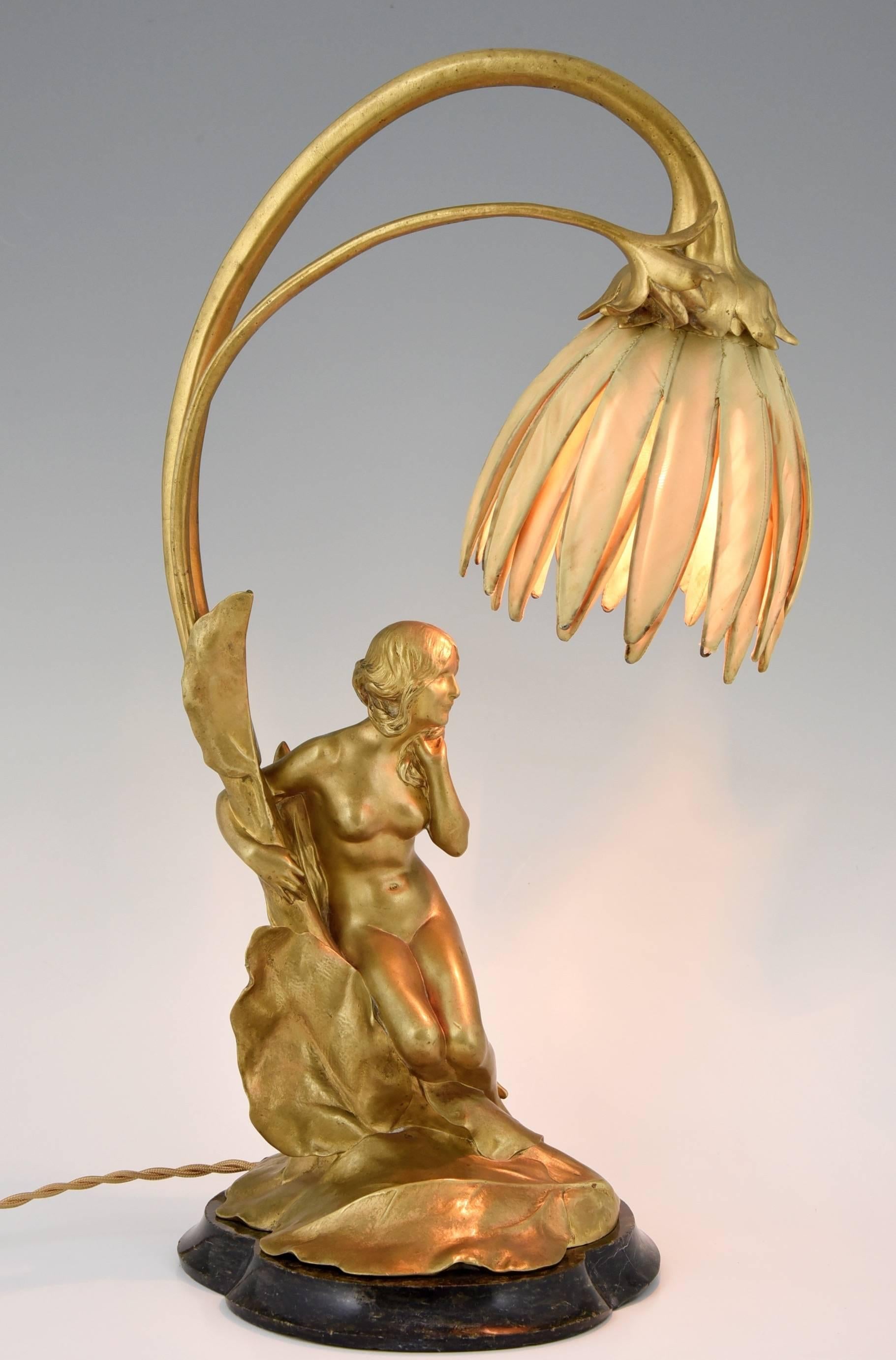 An Art Nouveau gilt bronze lamp in the shape of a flower with a seated nude.
By Maurice Bouval. Born in Toulouse (1863-1916).
Foundry seal Colin.
Material:  gilt bronze.  Marble base.  Original shade.
Origin:  France.

Size: 
H. 19 inch x L.