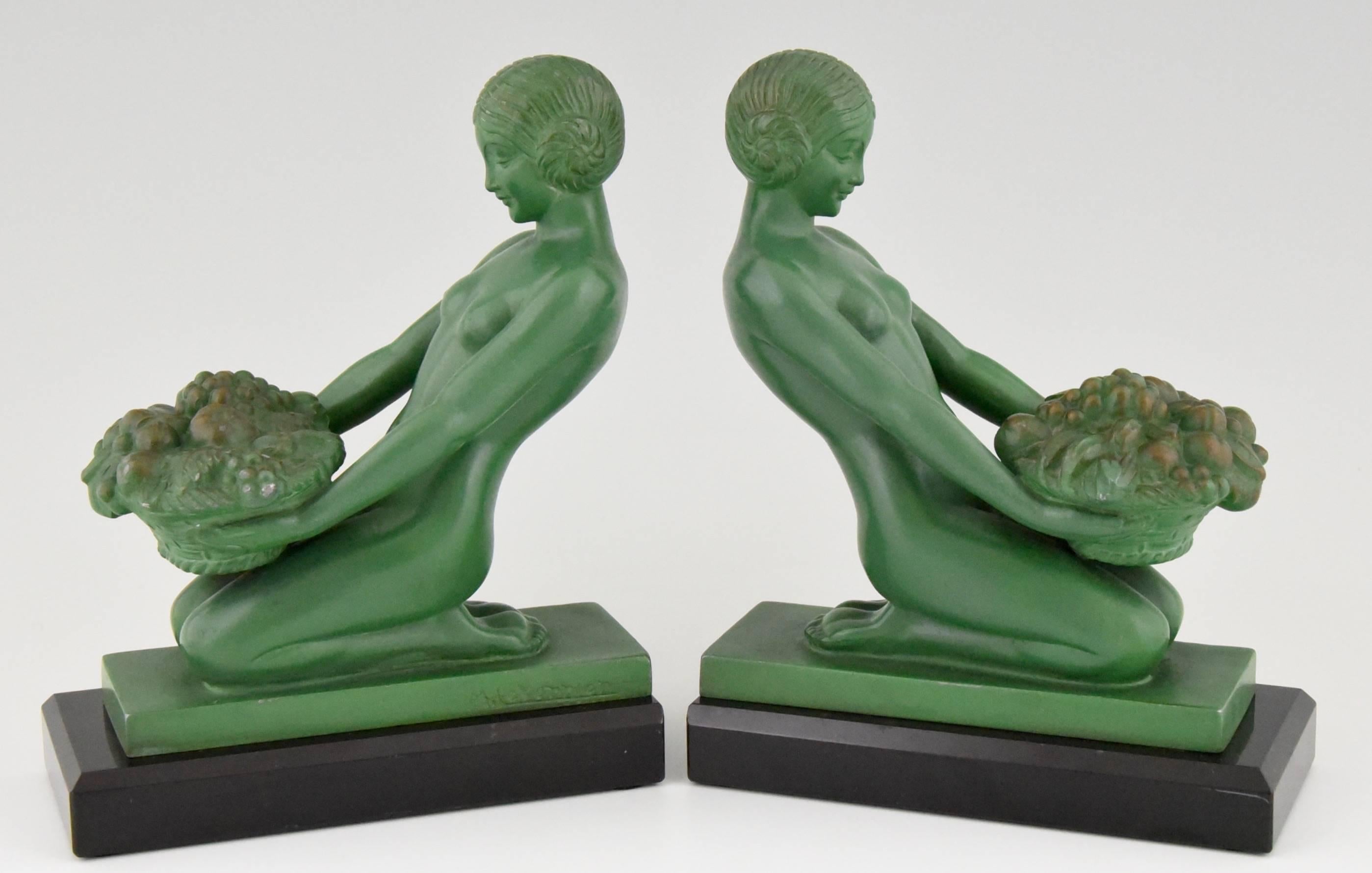 A pair of Art Deco bookends with kneeling nudes holding baskets full of fruit. 

Artist / Makera.
Max Le Verrier. 

Signature / Marks: 
M. Le Verrier. 

Style:
Art Deco.

Date:
1930.

Material: 
Green patinated metal.
Black marble