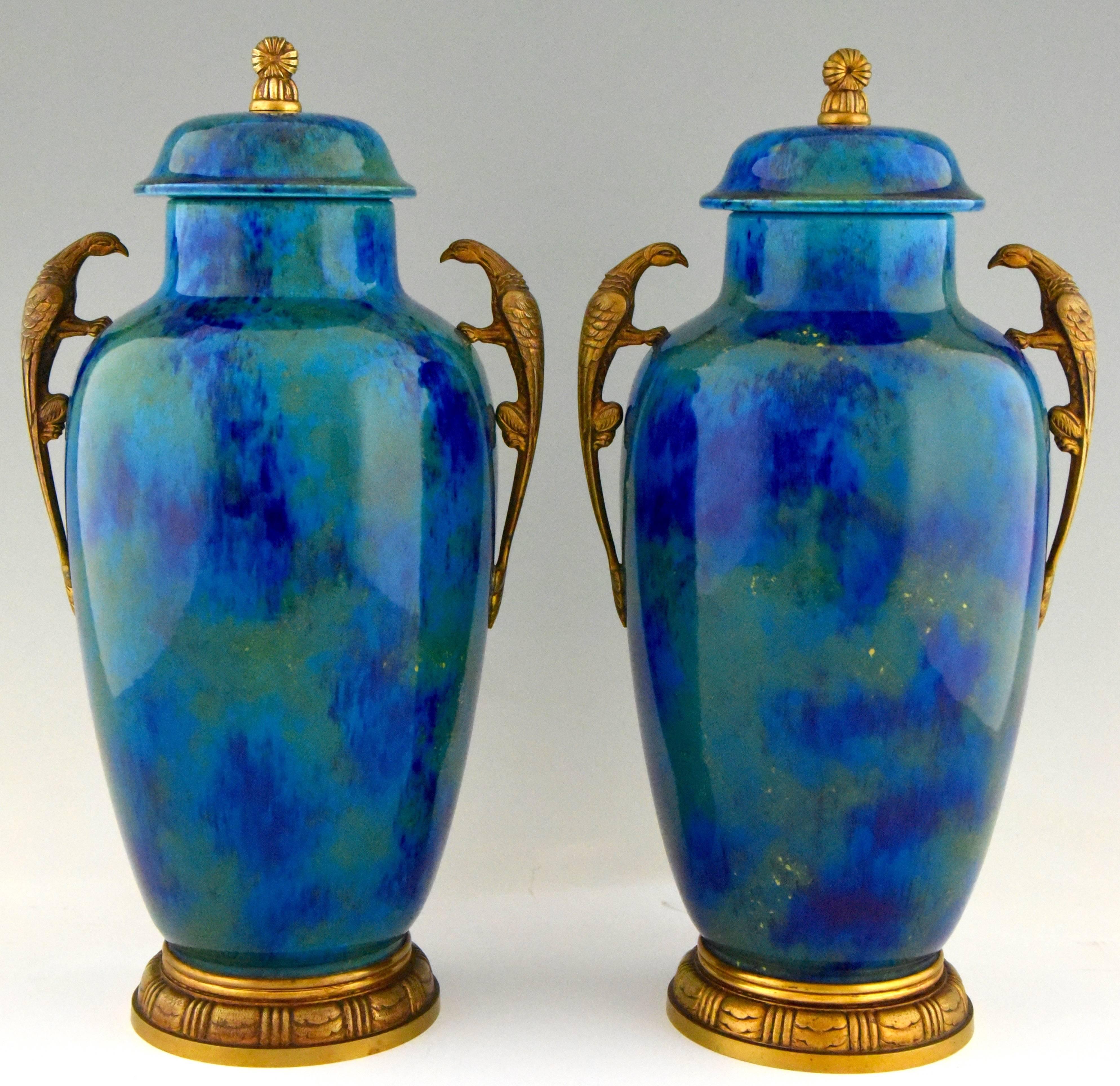 Pair of impressive Art Deco vases of baluster form with covers. A beautiful glaze in various blue, aqua, green and gold tones. The vases are raised on a gilt bronze feet, have bird shape handles and are marked P.M. Sevres.
Artist/ maker: Paul Milet