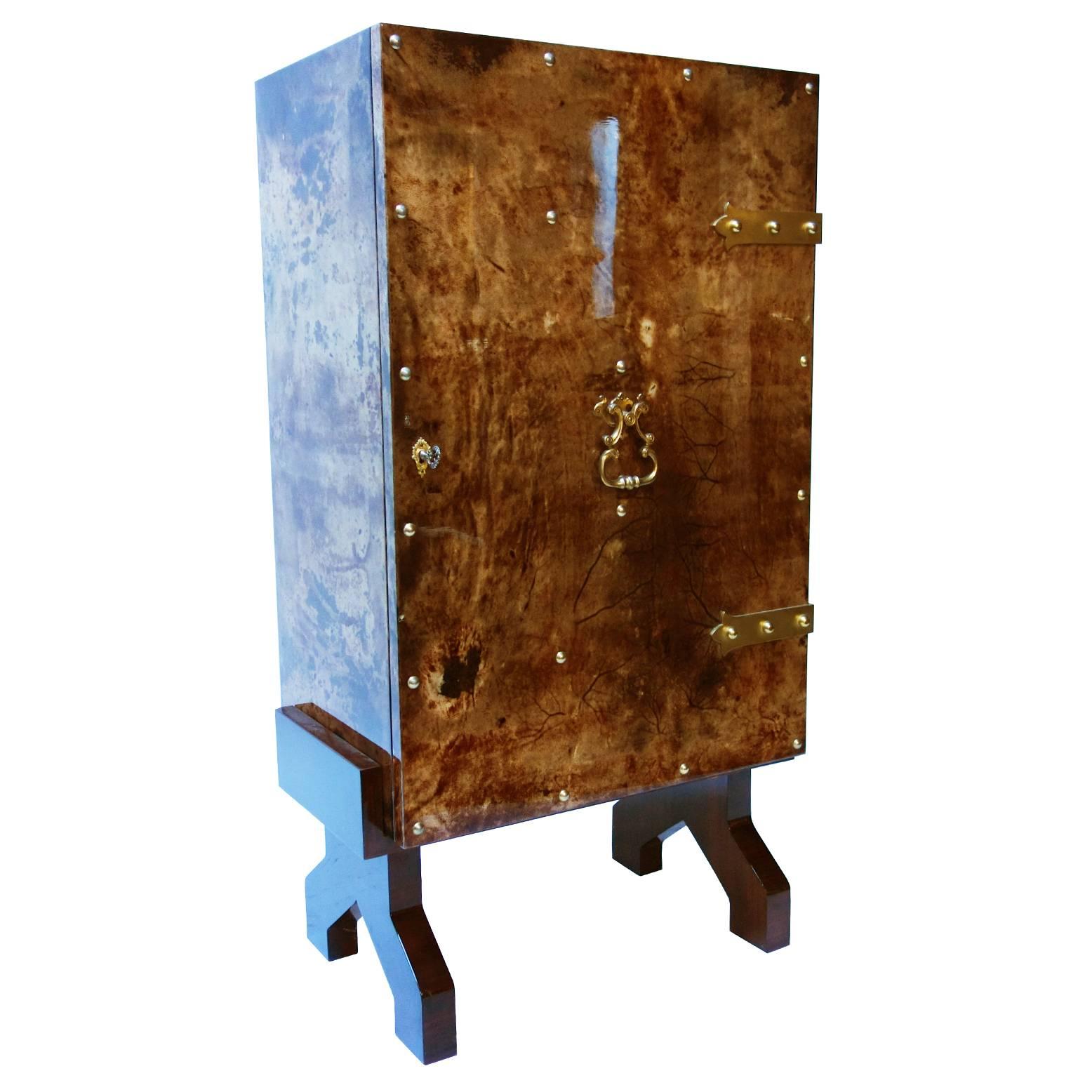 Italian drinks cabinet by Aldo Tura in tortoise lacquered goatskin with brass stud design hardware. The Mid-Century design is illuminated by a central down-lighter and features one-door with two shelved spaces, central shelved bar mirror lined