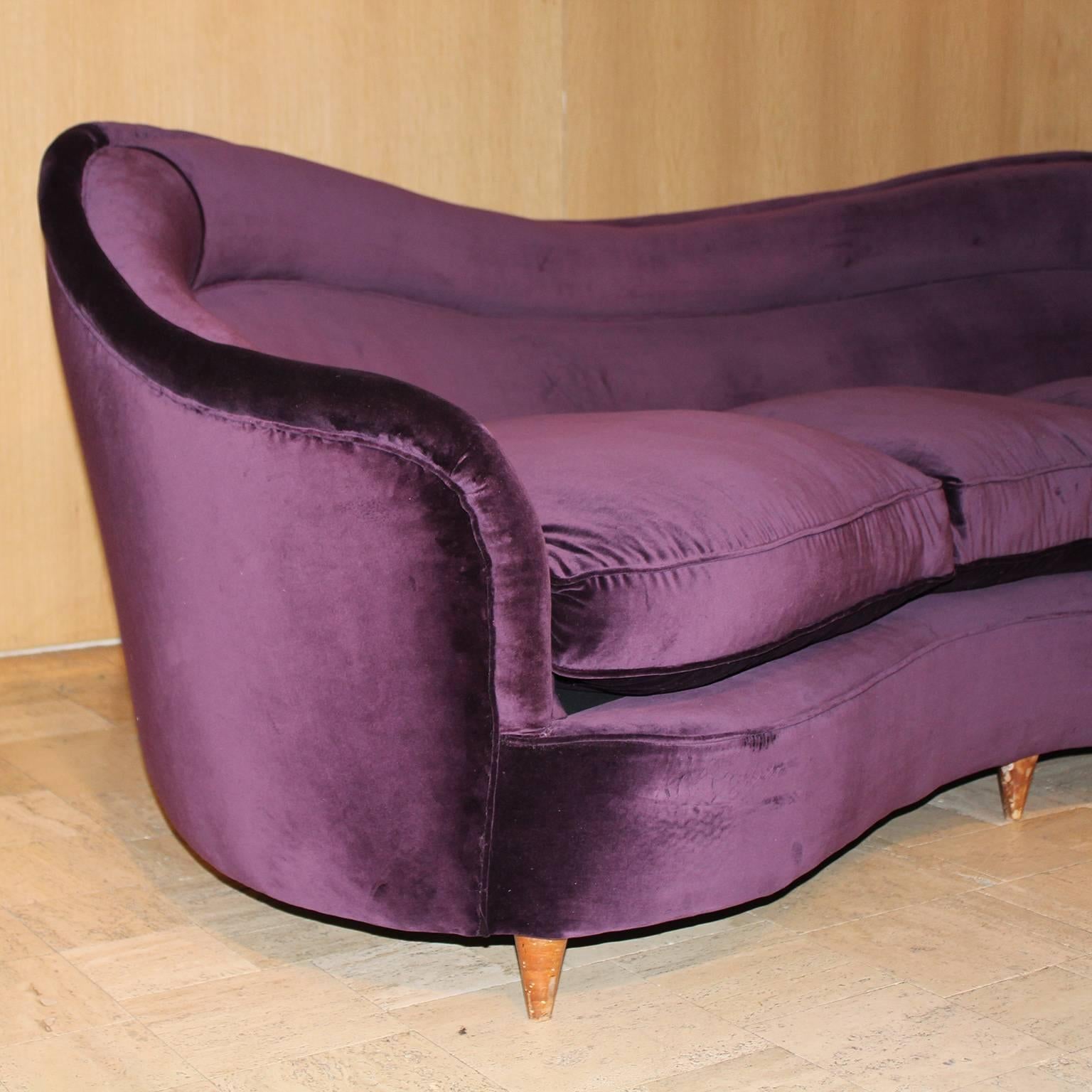 Curved Italian sofa newly upholstered in deep purple velvet with wood legs.