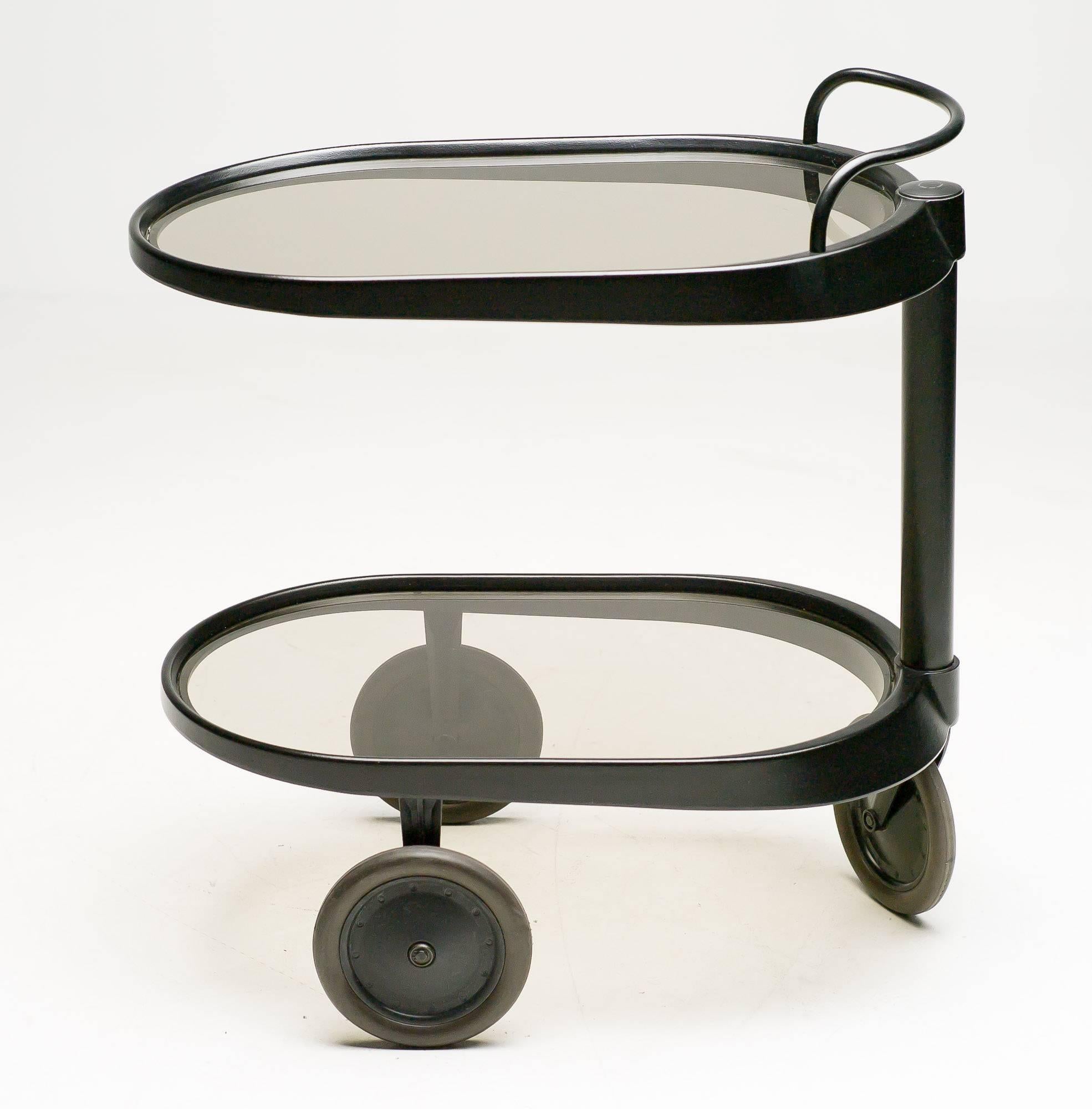 Emsta trolley, bar card.
Designed by Enzo Mari for Alessi in 1989.

Handlebar above a cylindrical shaft side support, on three wheels, stamped Alessi.

In black with smoke glass, very elegant.

We offer museum quality crating and affordable