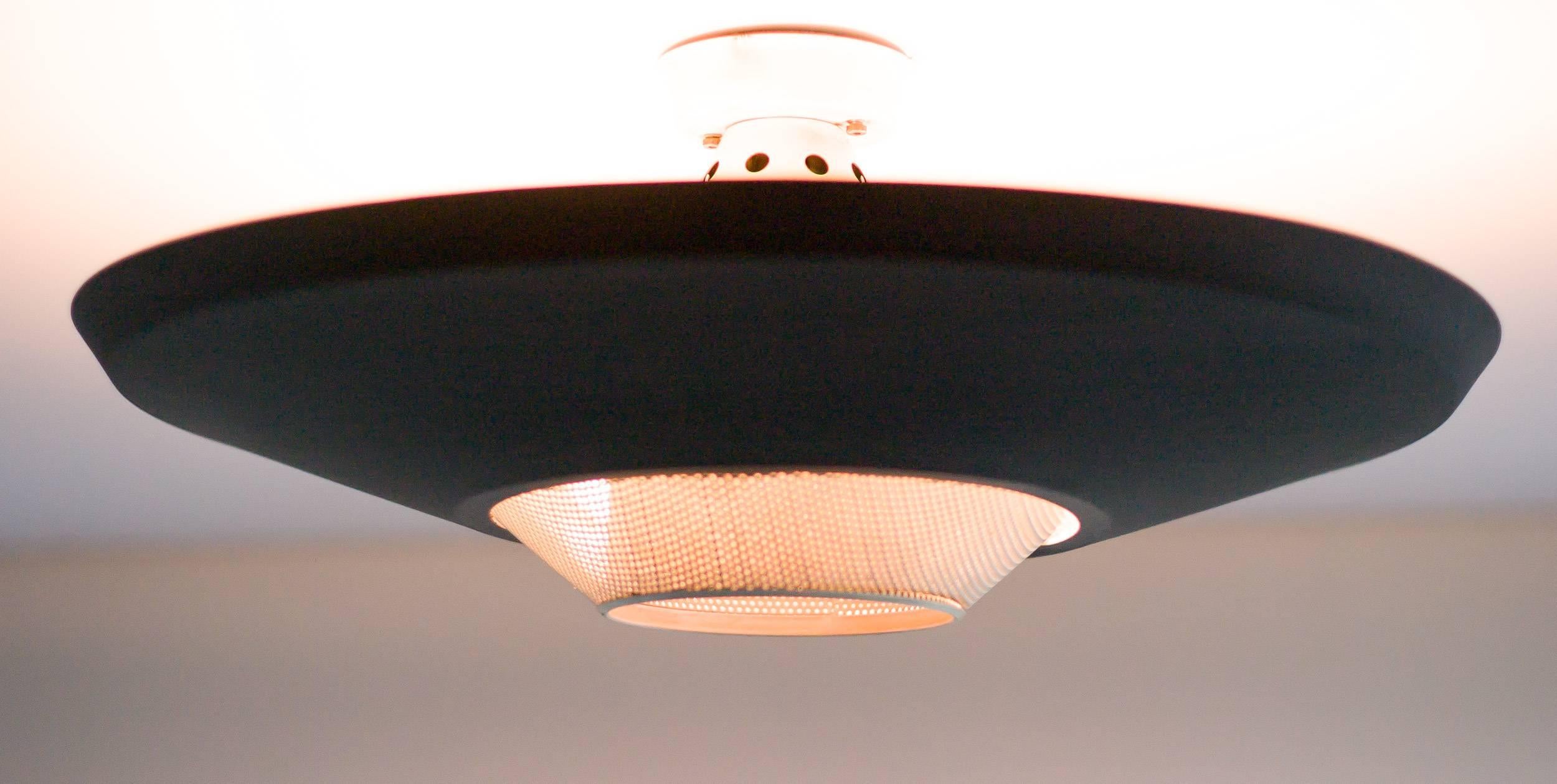 Industrial flush mount ceiling lamp designed by Louis Kalff for Philips. Matte black enameled shade with white enameled perforated centre shade to house a downward spot light, with three light bulbs above the black shade. 

Excellent fast and