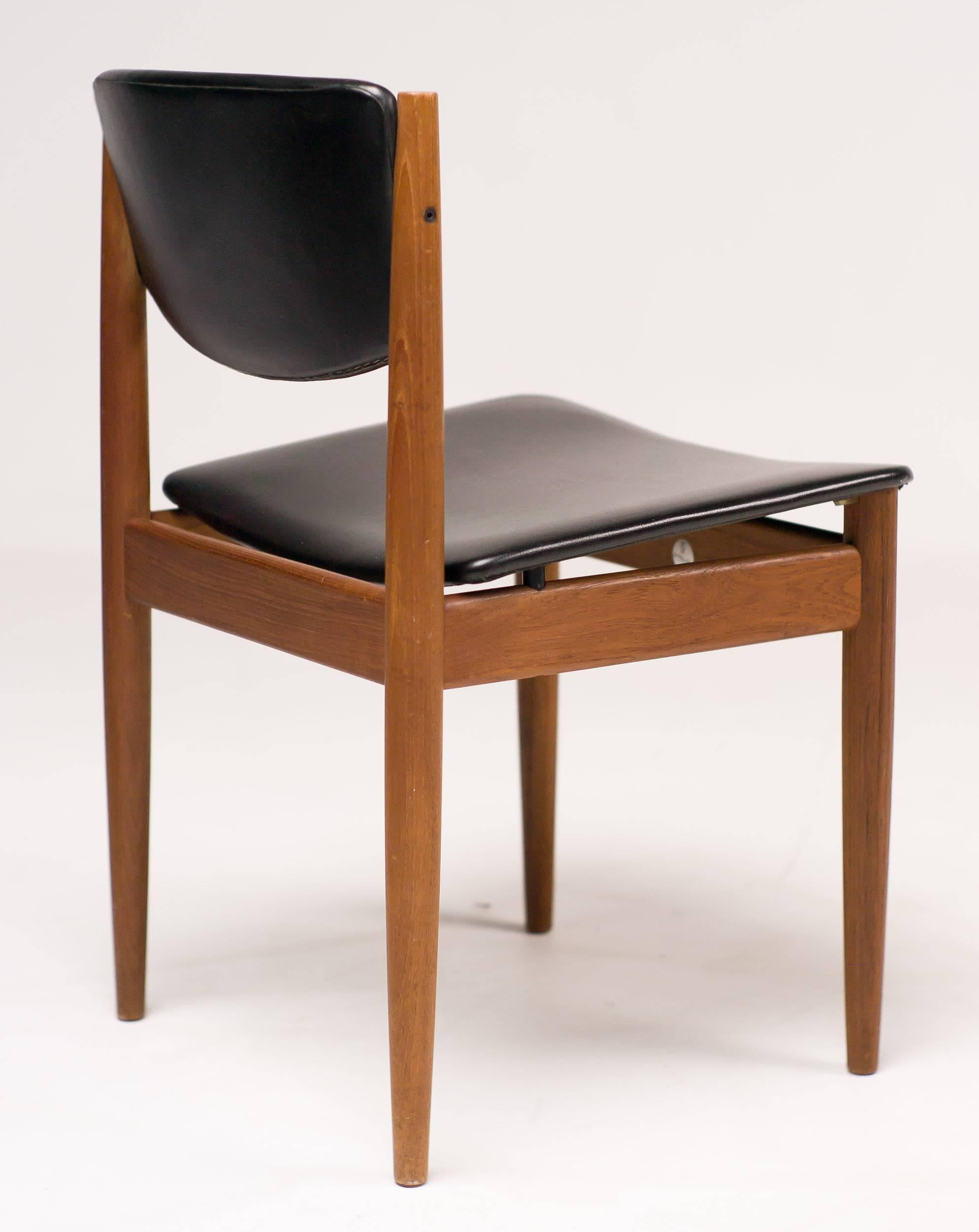 These elegant chairs are made in Denmark and bare the original manufacture silver label underneath. They maintain their original black vinyl upholstery that is in excellent shape, except for two very small splits in the vinyl on the back of one