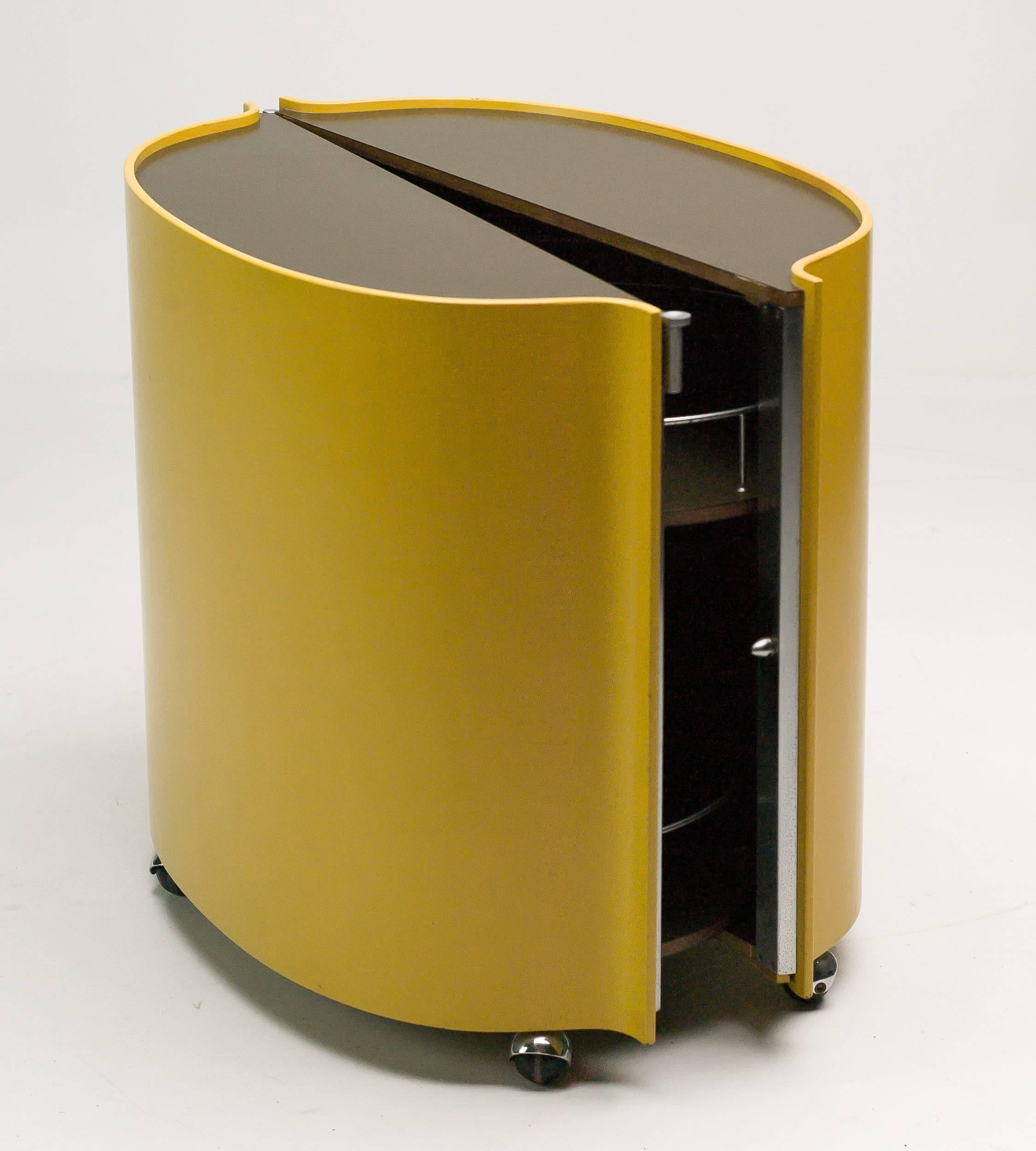 Bar on wheels by Eugenio Gerli for Tecno Milano, 1966.
Plywood outer panels lacquered in bold yellow. Beautiful bookmatched rosewood veneer inside, top and shelves with chocolate brown formica and matte chrome steel hardware. Matte chrome steel