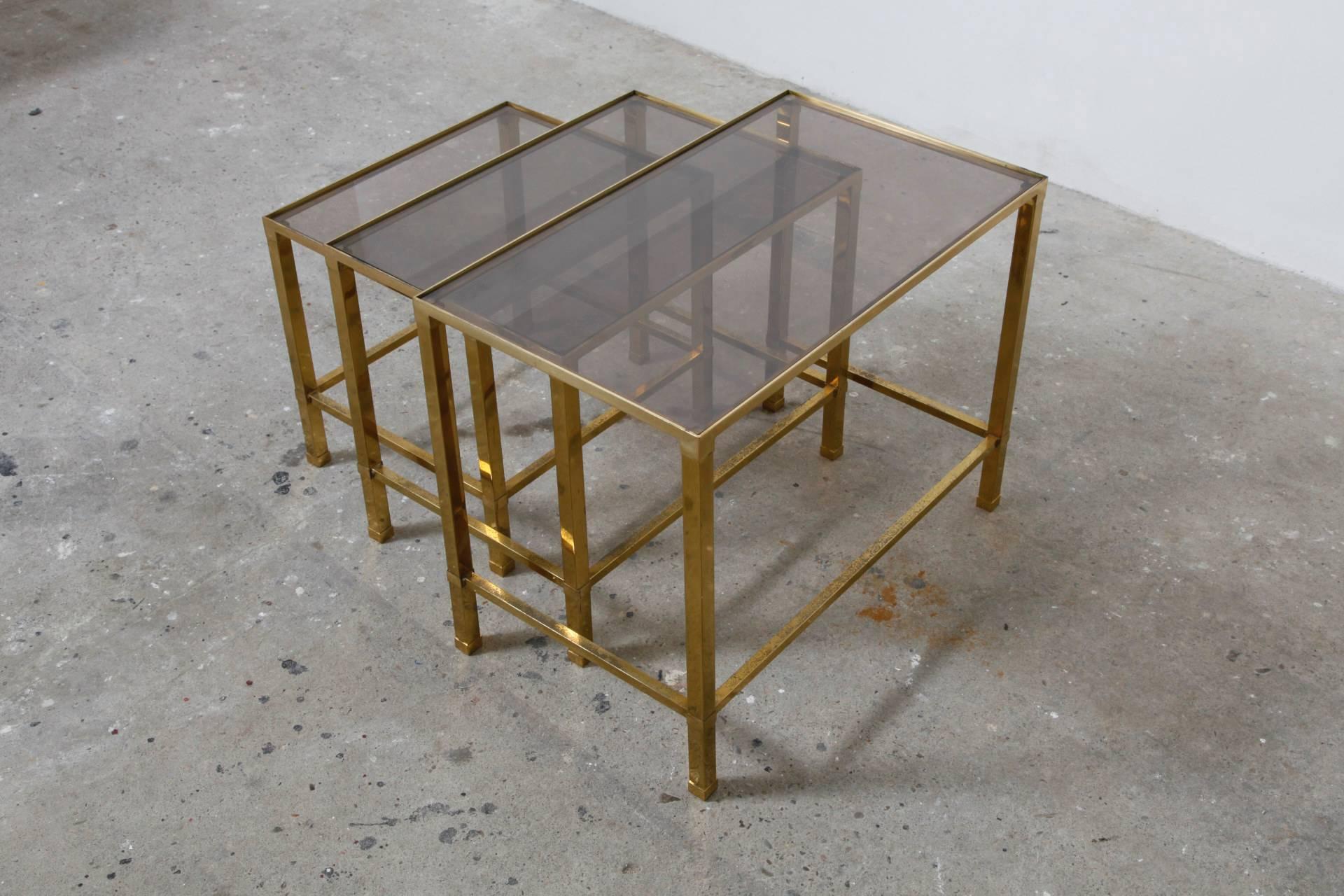 A set of three brass nesting tables with clear glass tops in very good vintage condition. 
