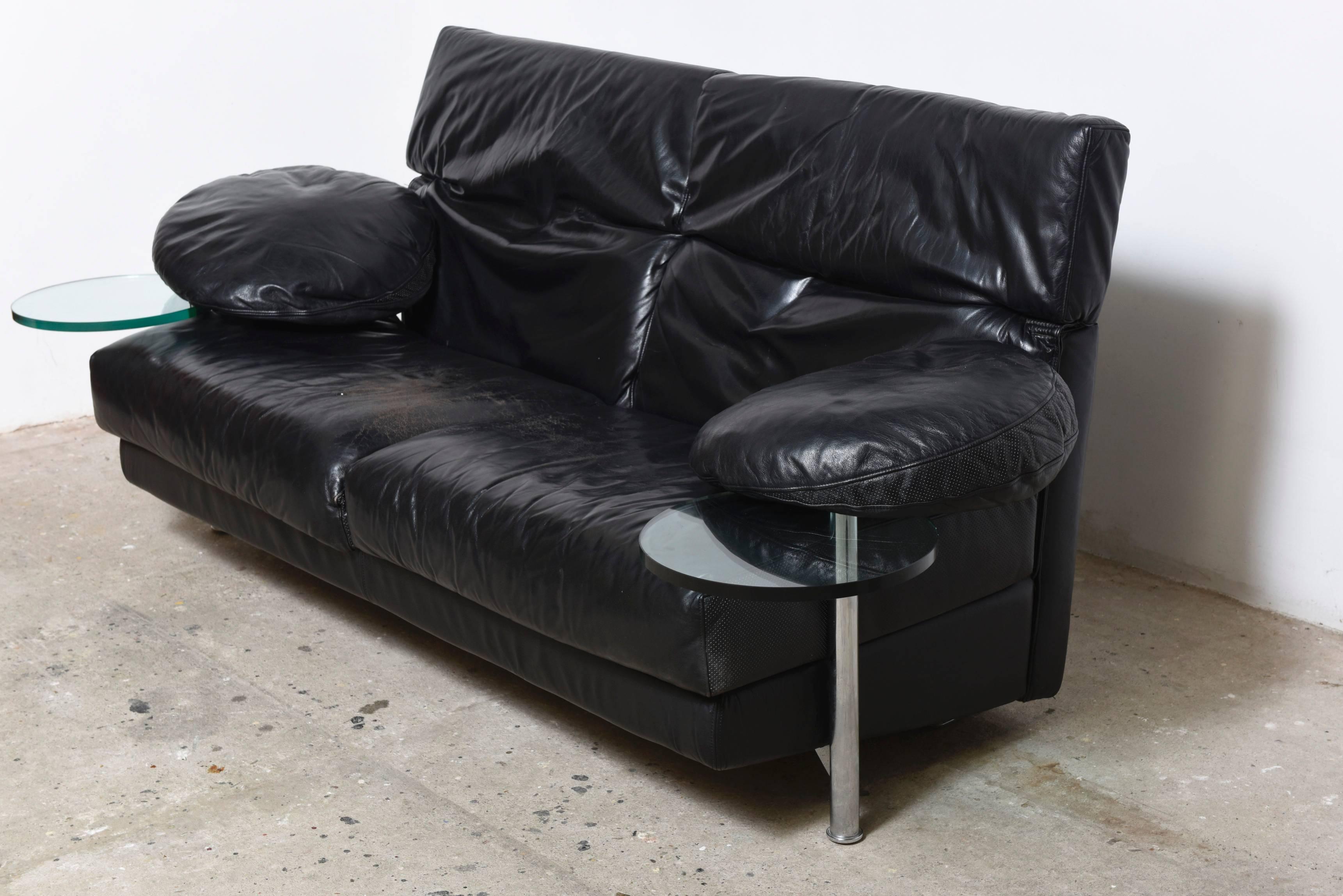 Arca two-seat, couch with right and left armrest provided with transparent glass serving tables which swing out from under the leather armrest.

Framework made of structural steel and black leather.

The backrests, which are easily adjustable,