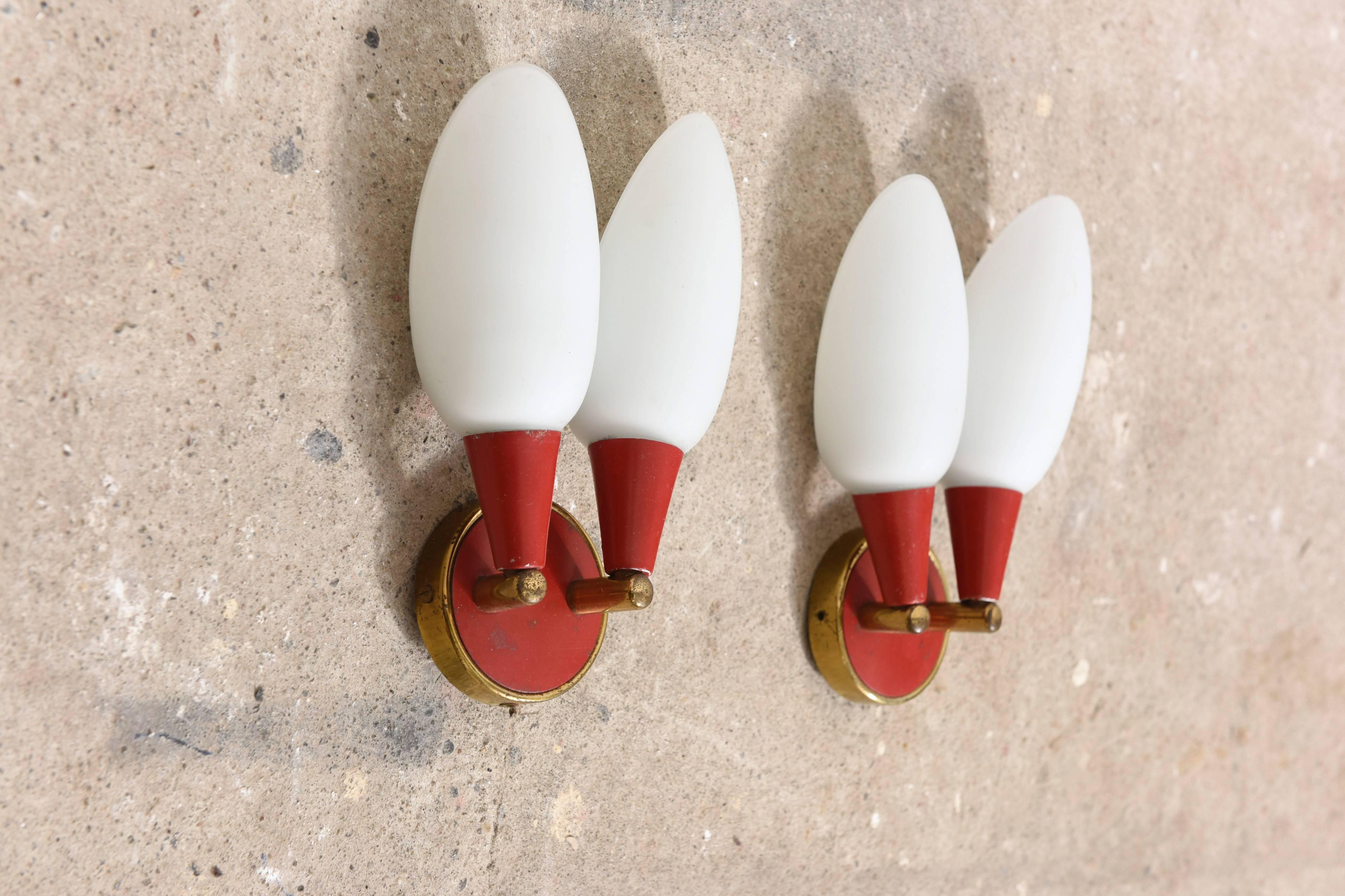 Excellent pair of wall lights, very nice elegant shape with soft light spreading.
The red coated frame with brass accents are in nice contrast with the white opaline shades.
 