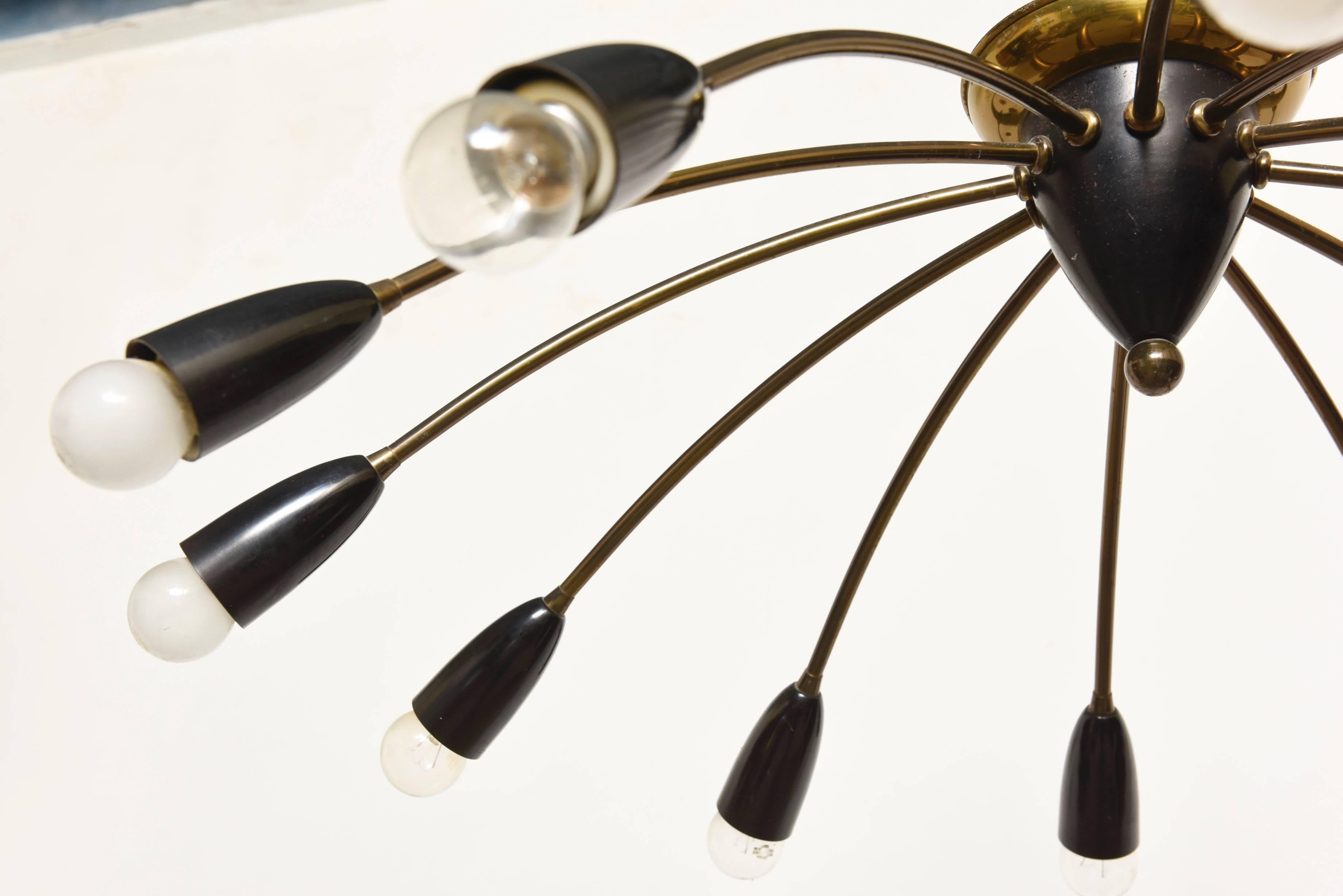 Large Sputnik chandelier, produced in Italy, circa 1950s, Stilnovo.
With 12 curved arms in brass, each terminating with a rounded socket cover in black enamel.
Wiring and sockets to US standard.
Very good condition.