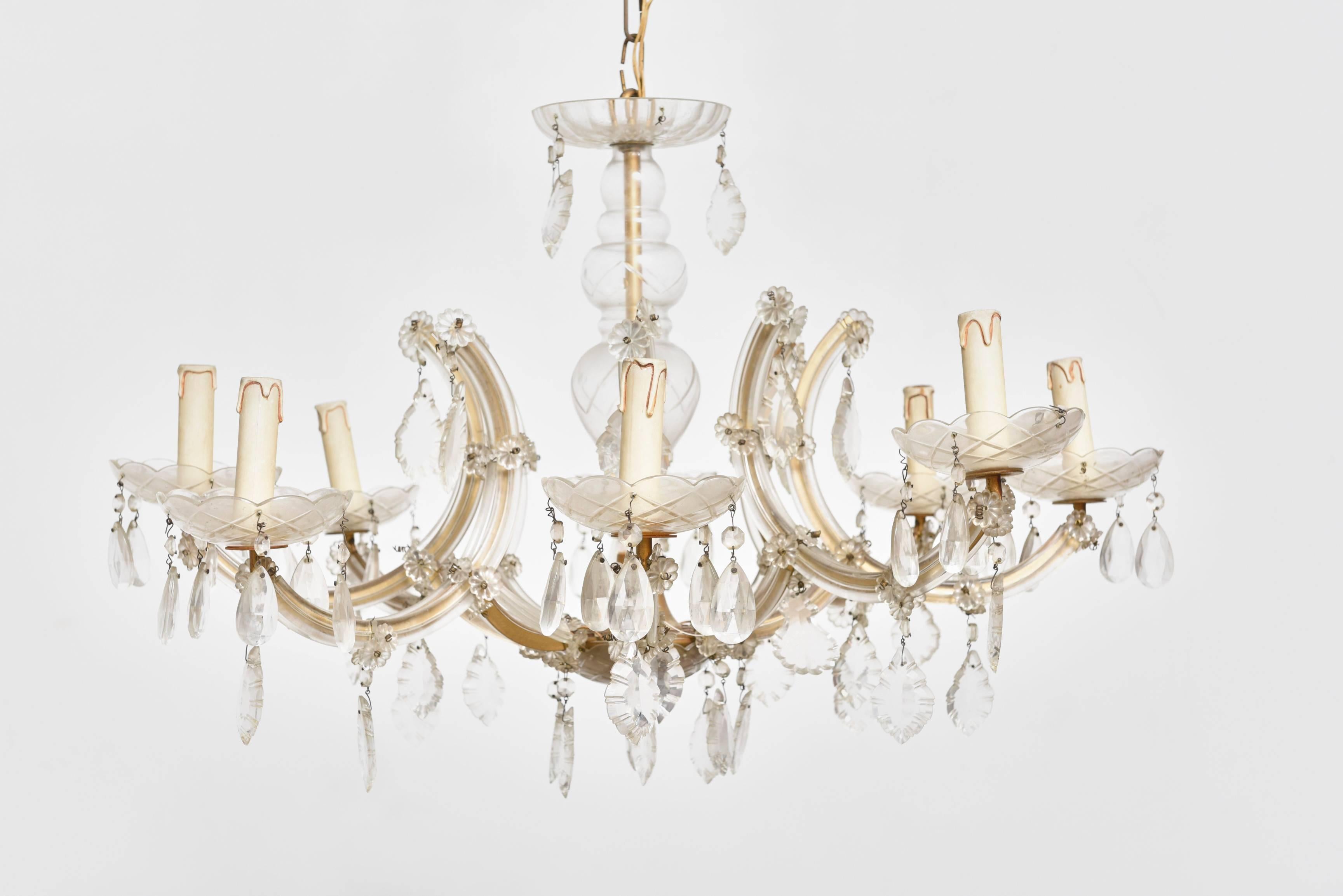 The Marie Therese 8 light chandelier has a flat metal frame but this is almost entirely covered in glass. Curved glass plaques or’ listels’ as they are known cover the arms. Glass drip bowls feature on every arm and the central column is also glass