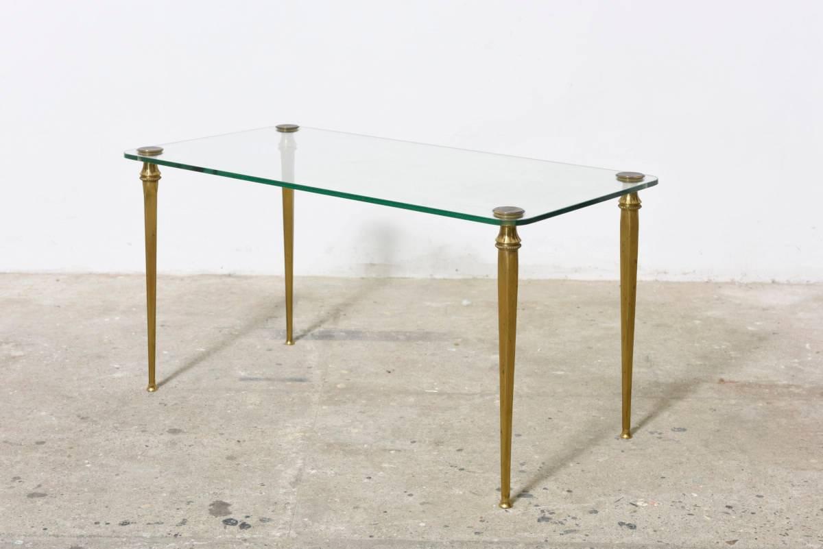 This very elegant cocktail table with four solid brass feet that pierces and supports the glass top. Light, slender and well engineered, it is a great example of French design.