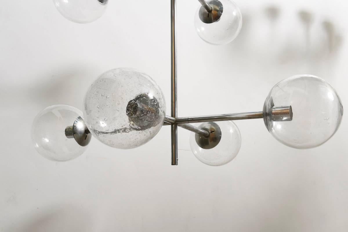Huge chromed light fixture with 12 lights clear blown glass globes.Labeled produced by Kinkeldey lamps in Germany, 1960s. A perfect chandelier for a hallway or an entrance from an office or a hotel, possibility of shortening the pendant, length