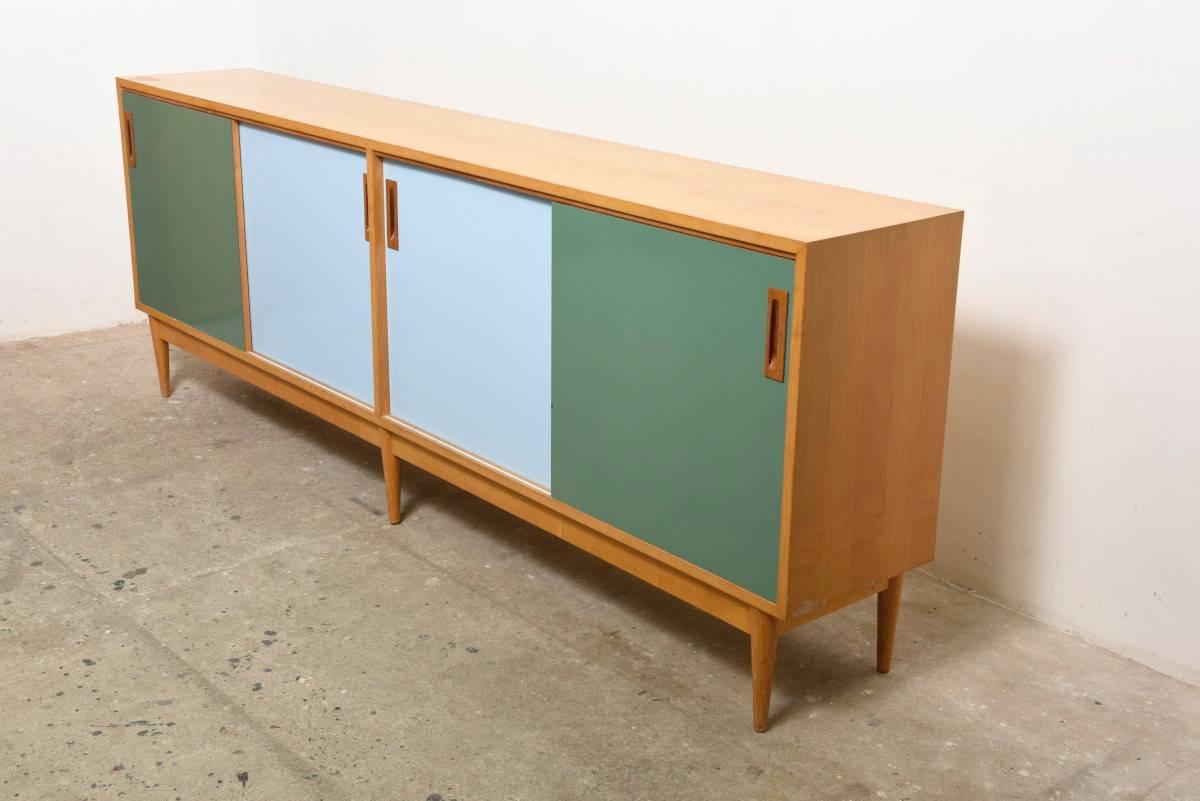 Large sideboard designed by Jos De Mey for Van den Berghe-Pouvers, Belgium. Made in walnut with a beautiful grain, sliding doors in green and blue, this piece would make a wonderful addition to any modern interior.