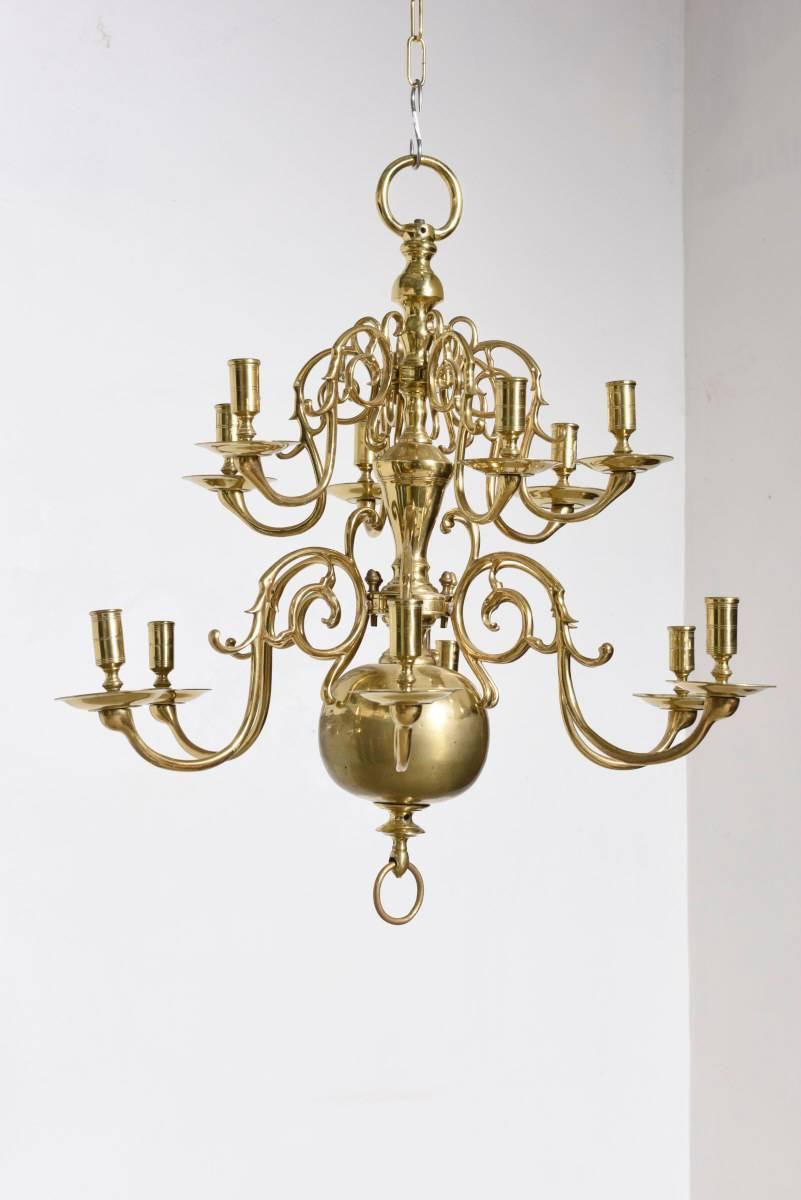 Charming large 18th century Dutch or Flamish solid bronze 12-arm chandeliers with patterned mounted branches come from a pillar ends in a large ball and ring.
A highly curved arms hold the candles on a level near the body of the chandelier's, each
