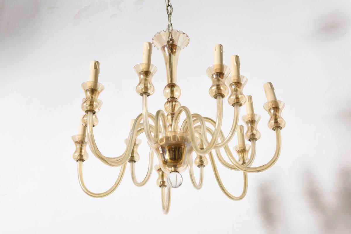 Mid-Century modernist handblown Murano amber glass twelve-arm chandelier. 
A dome-shaped centre with glass cap-detailing supports twelve handblown glass rods, each of which supports a candelabra socket. 

This stunning piece can would be ideal