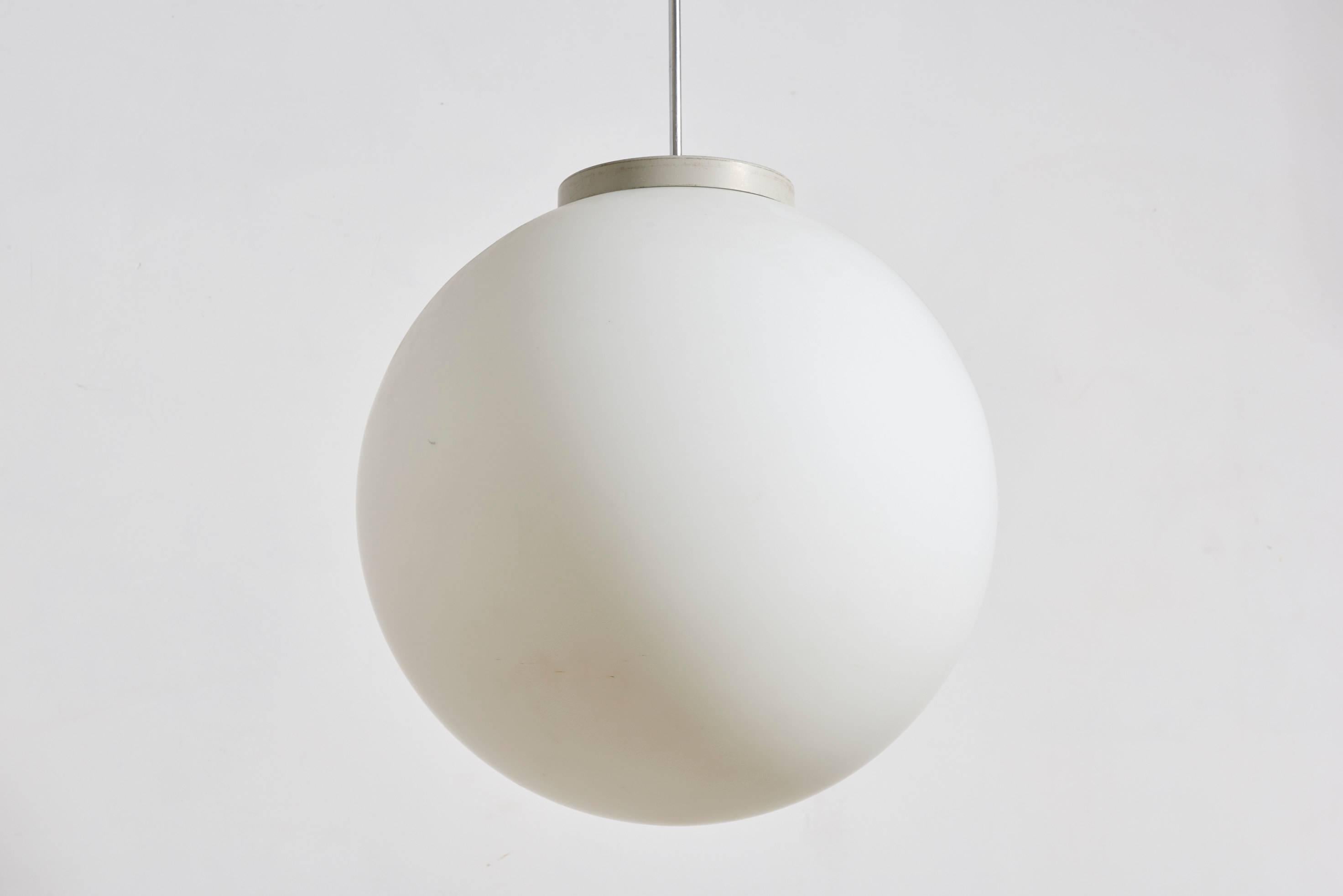 Executed in handblown satin white opal glass, chrome pendant tube, white bakelite canopy and white lacquered top, originally used for general illumination. 
 