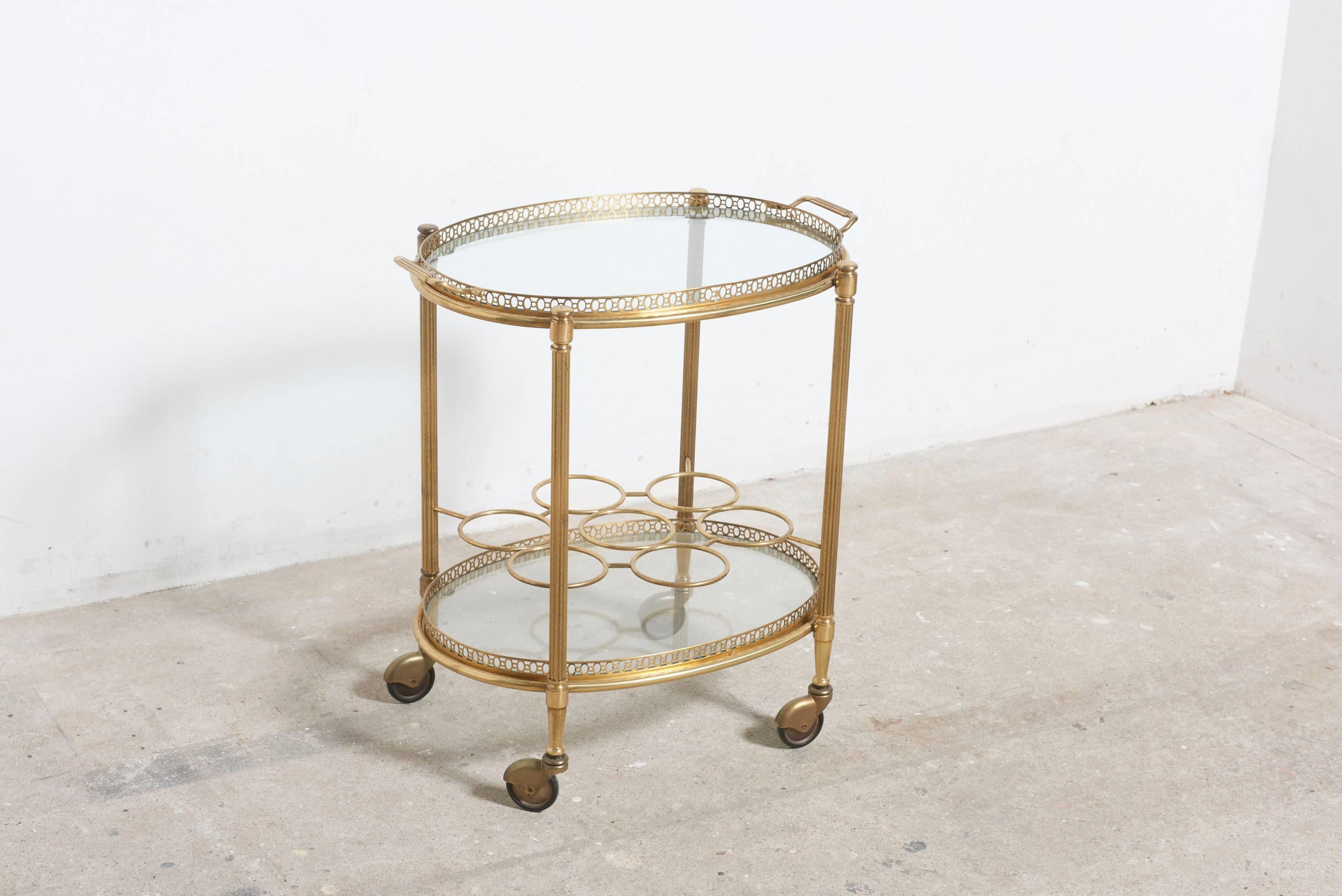 This very fine designed two-glass tiered oval polished brass bar and serving cart is simple and elegant, with a serving tray and two brass handles to push, a bottle rack for seven wine bottles, on rolling caster wheels.
Perfect for use as a side or