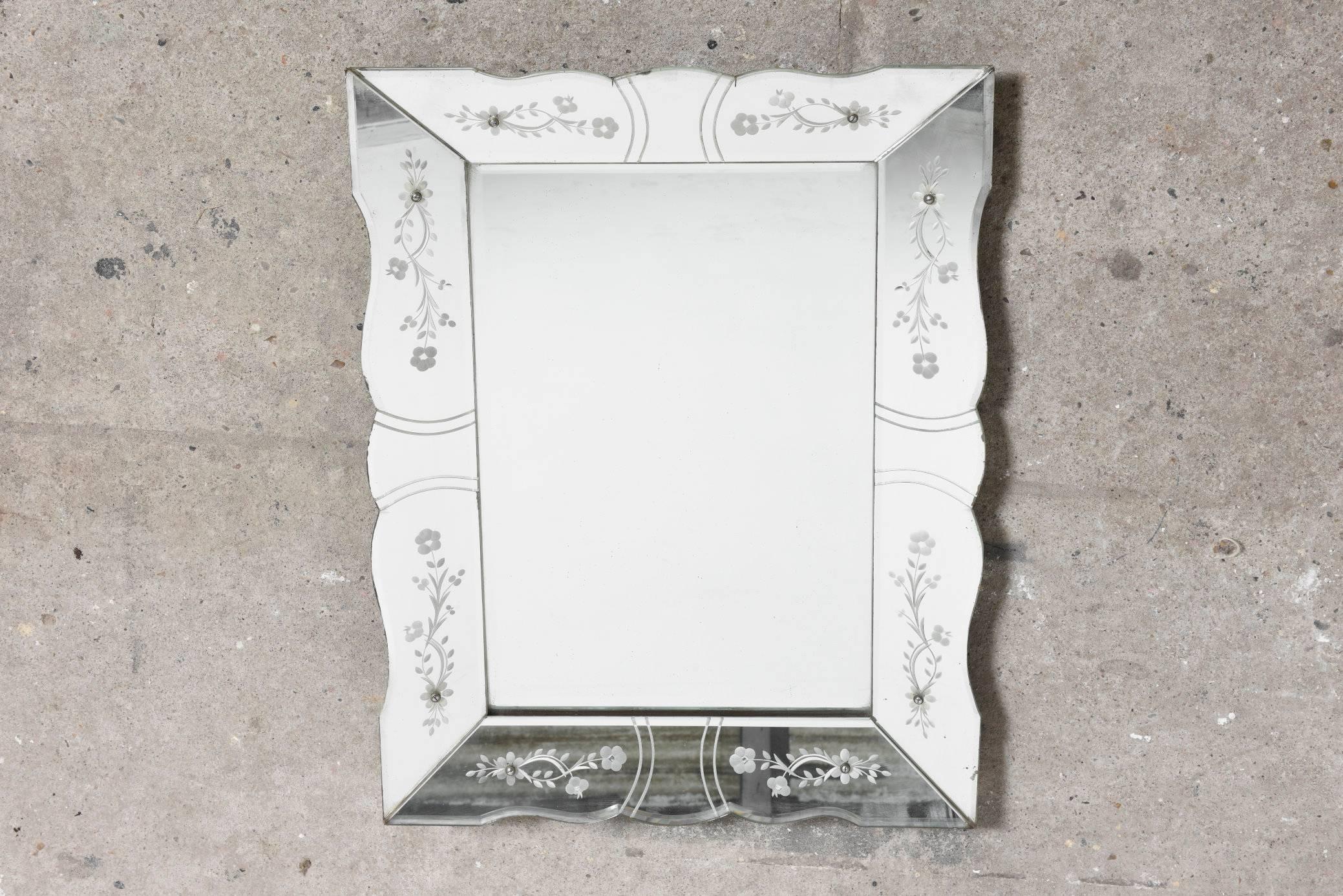 Vintage French wall mirror decorated with floral etched elegantly scalloped bevelled frame panels which surrounds a clear glass bevelled edge mirror. This piece is in overall good vintage condition, with no significant loss of silvering to the